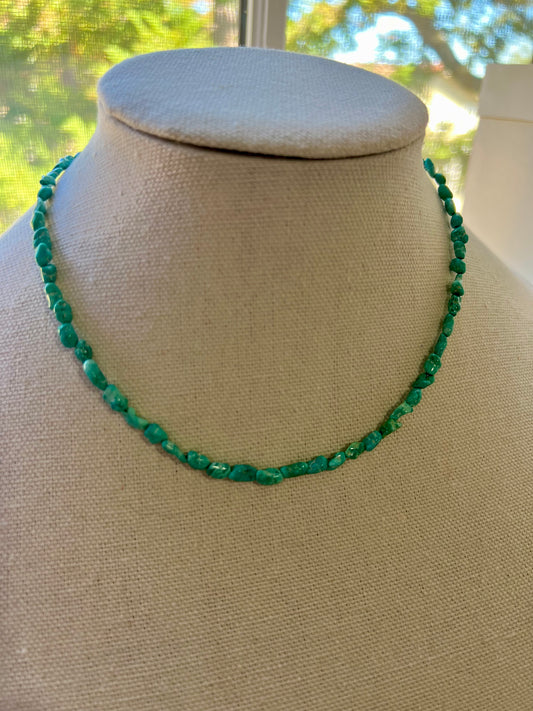 a green beaded necklace on a mannequin