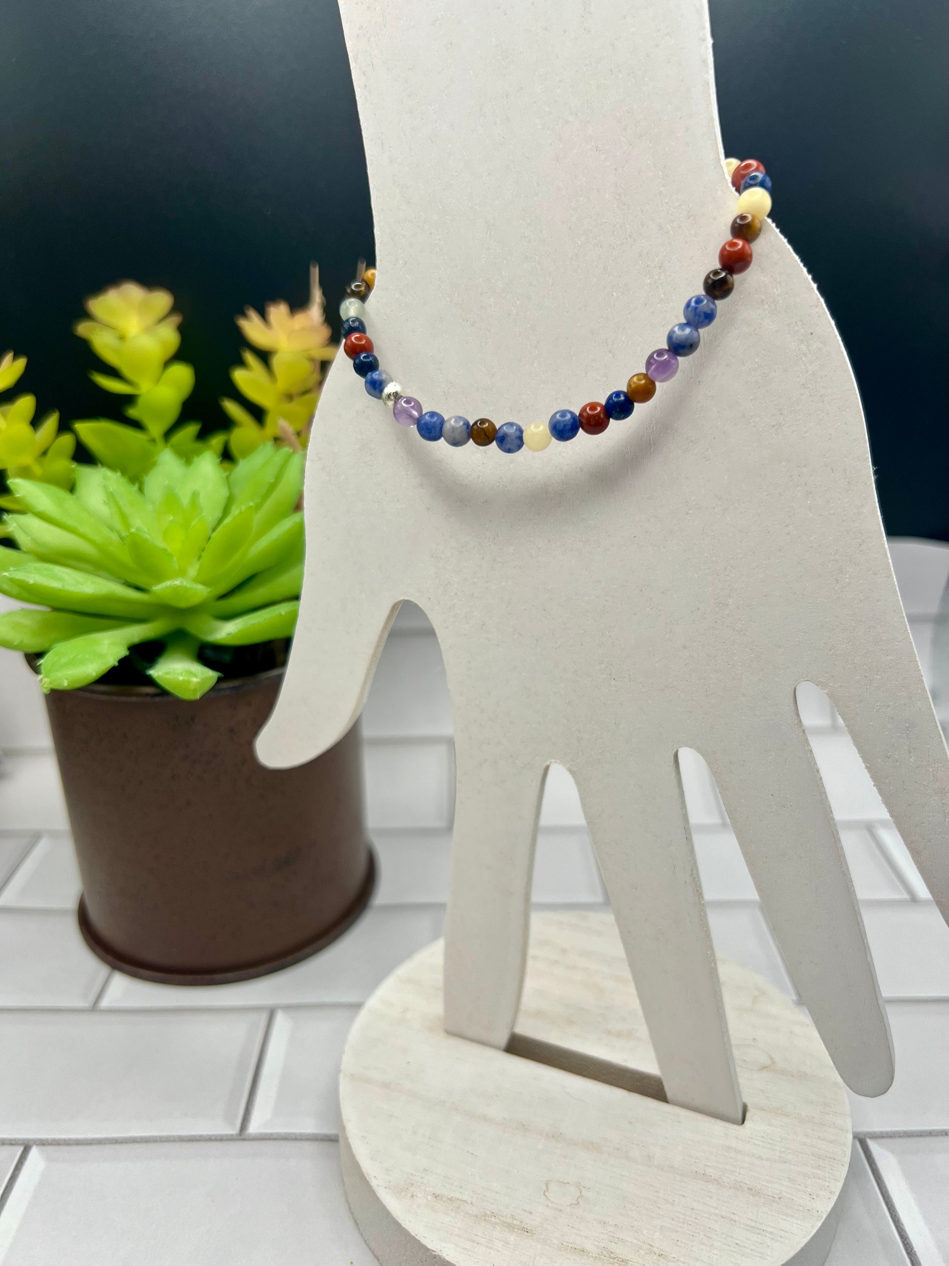 a white sculpture of a hand holding a beaded necklace