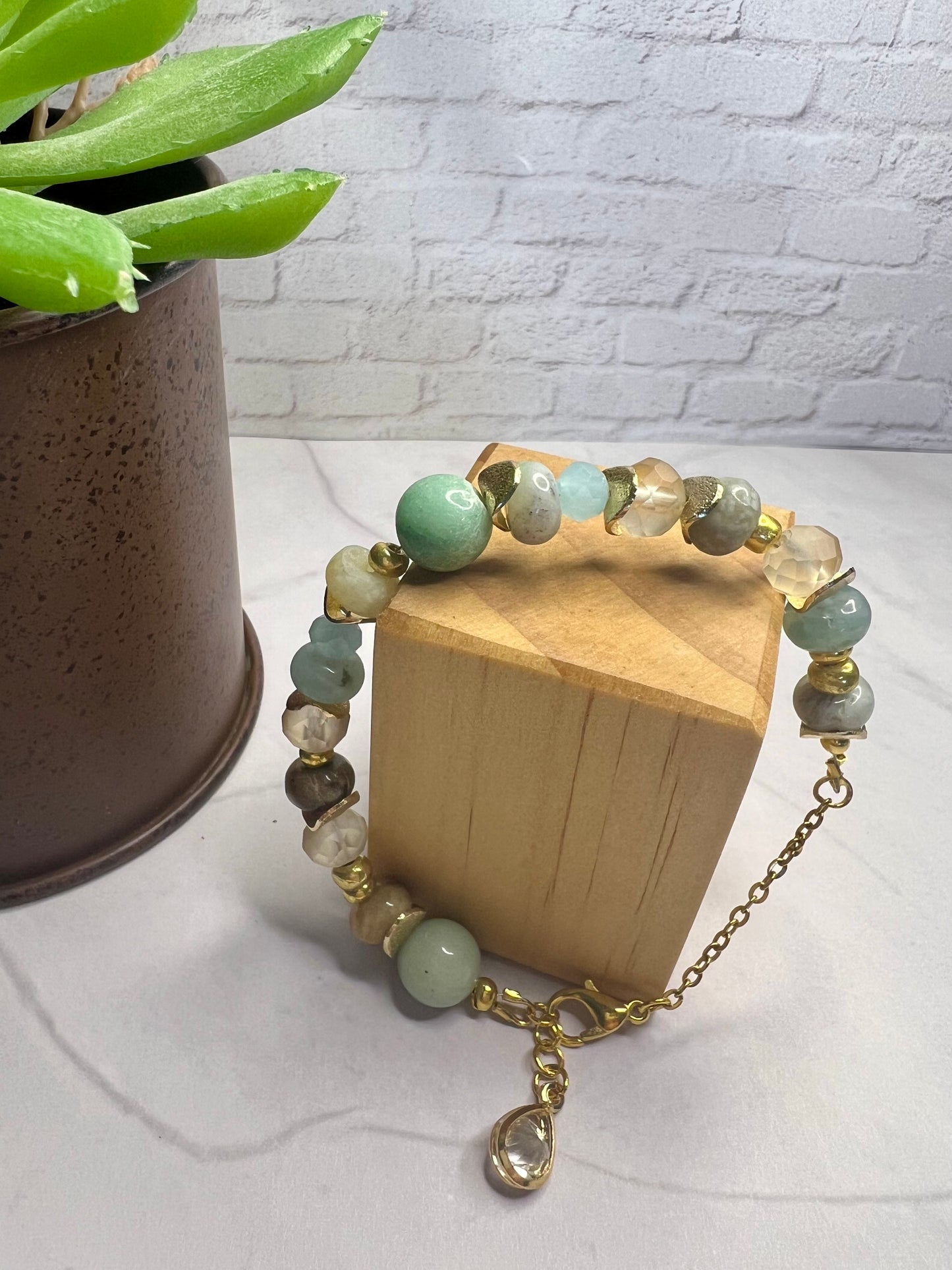 a wooden box with a necklace on it next to a potted plant