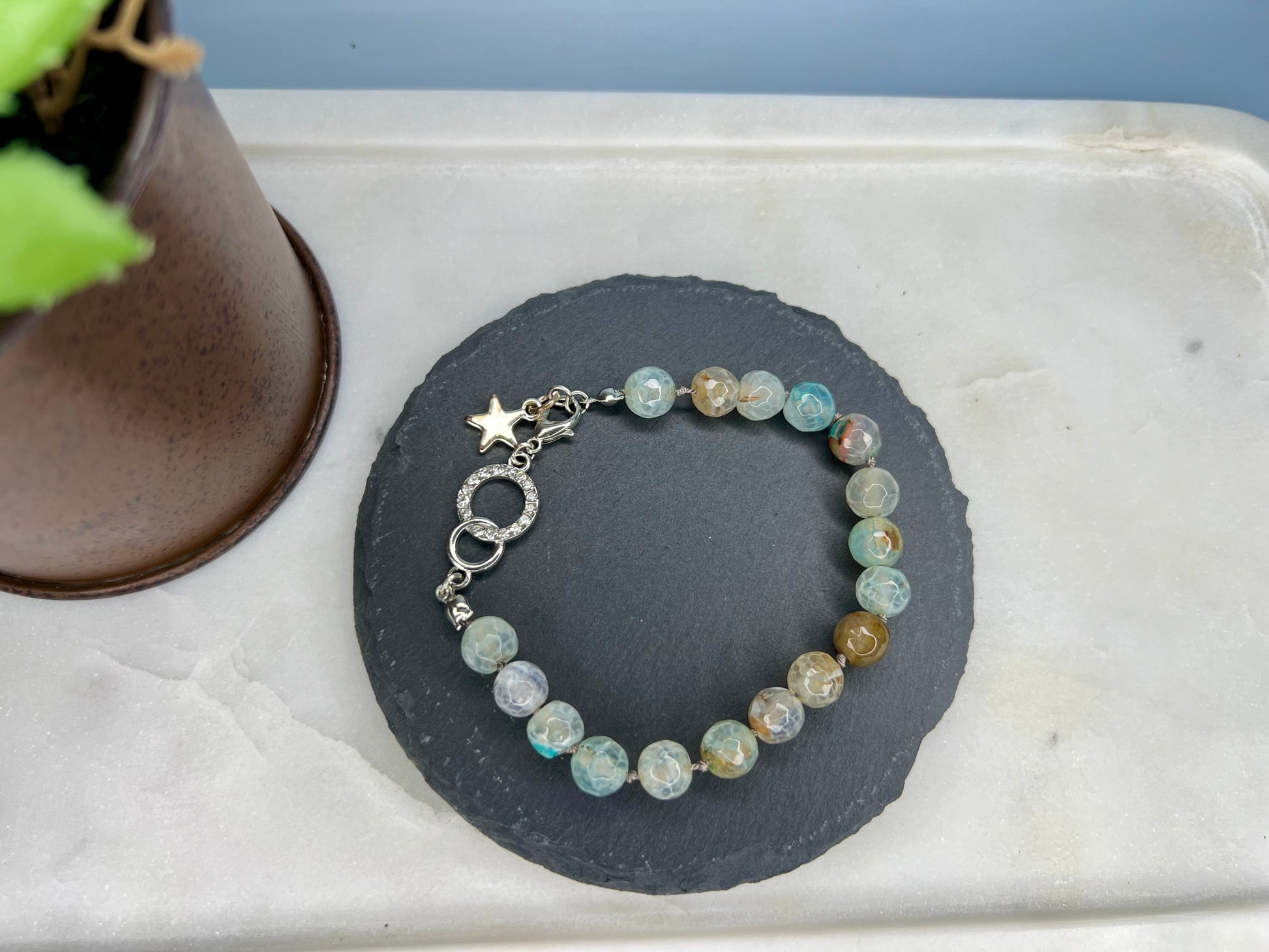 a bracelet with a star on it sitting next to a potted plant