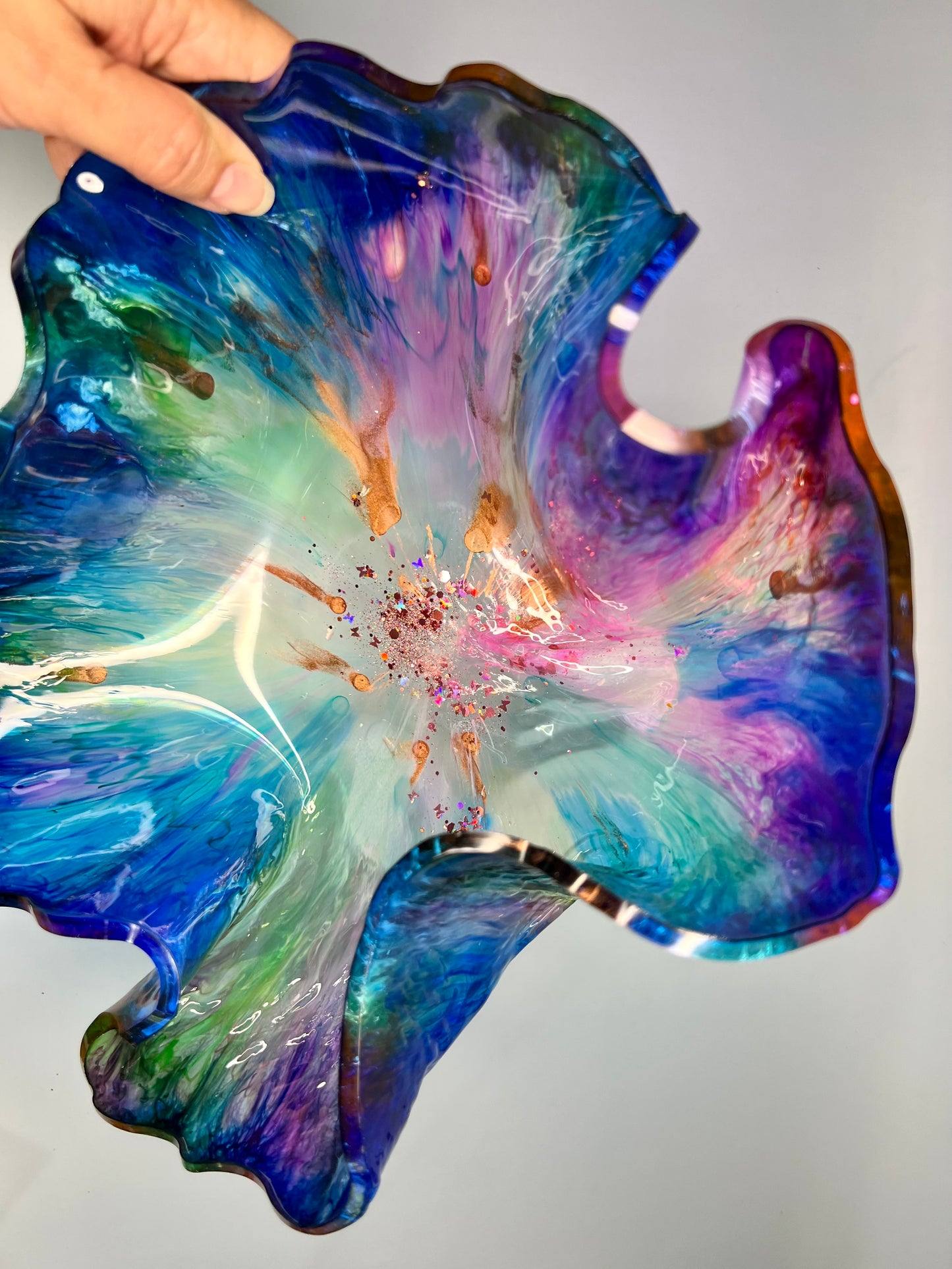 a hand holding a colorful glass flower dish