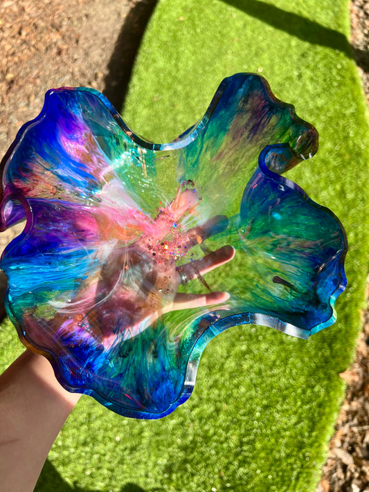 a hand holding a colorful glass flower dish