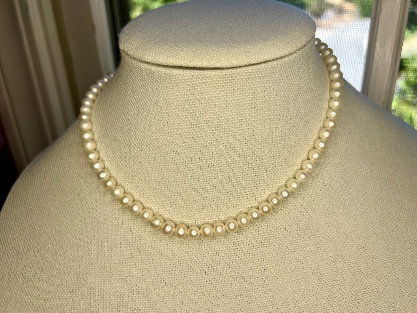 a white pearl necklace on a mannequin