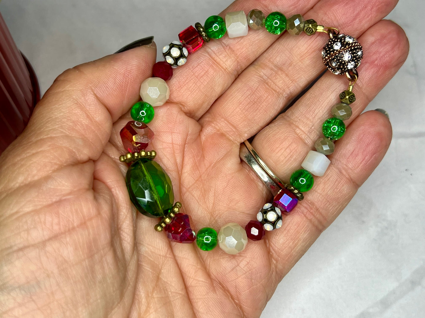 a woman's hand holding a multicolored beaded bracelet