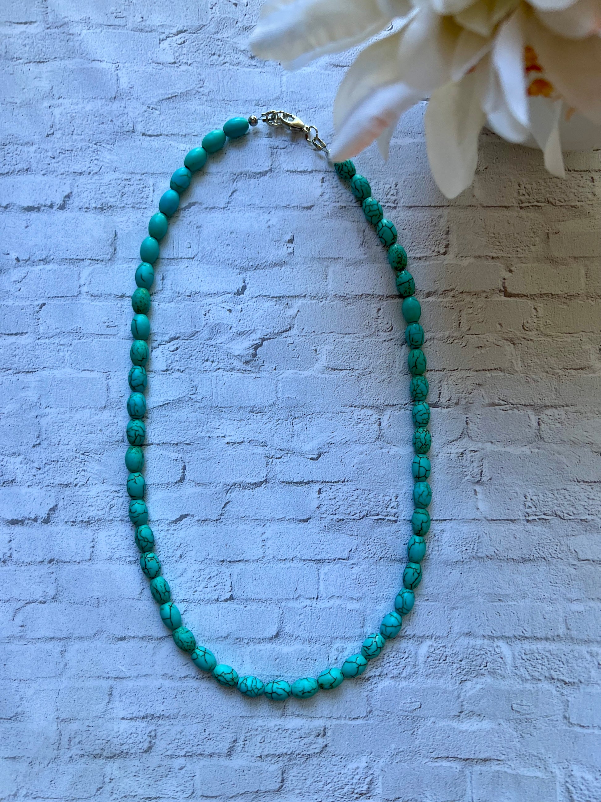 a blue beaded necklace on a white brick wall