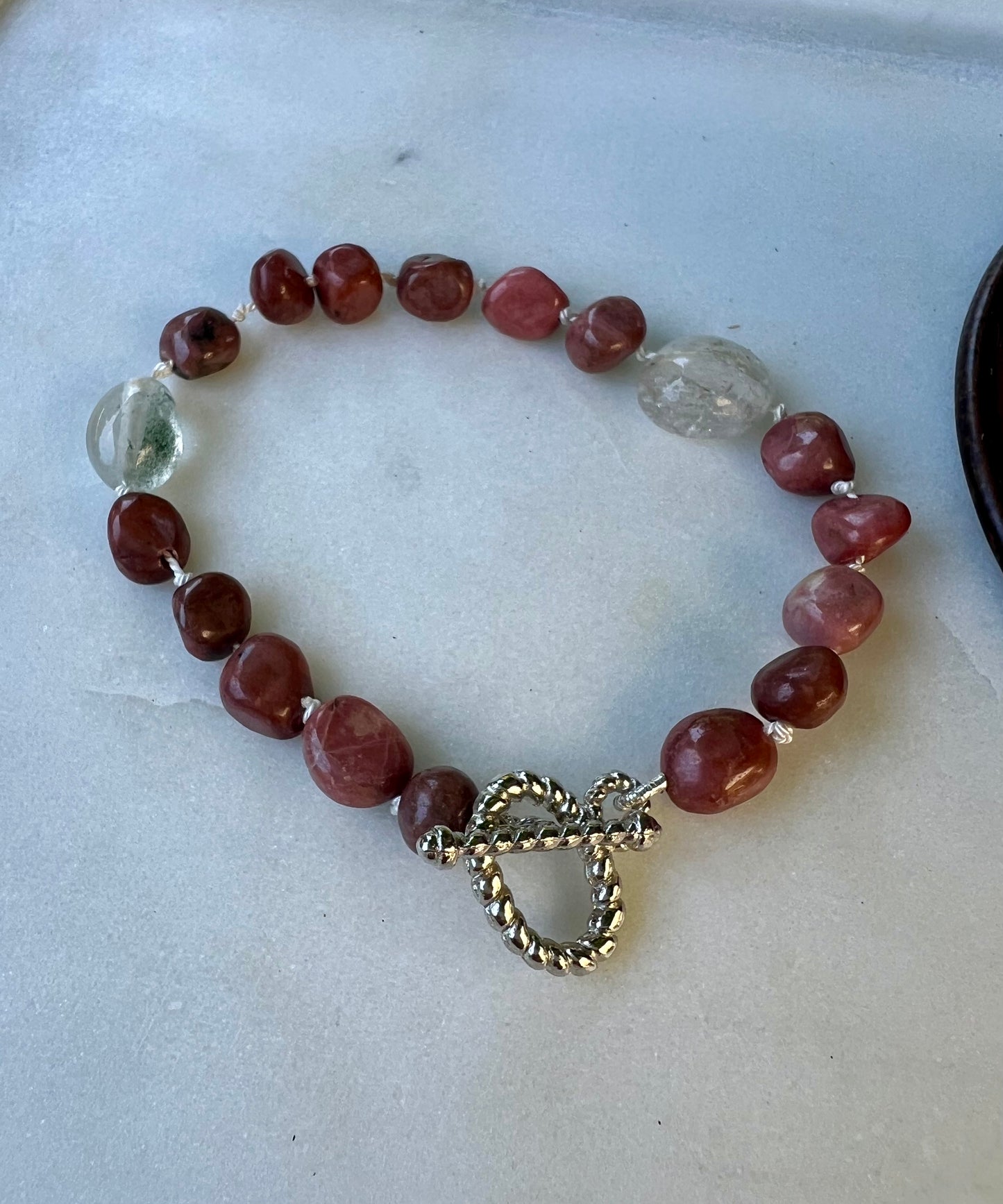 a red beaded bracelet with a heart charm