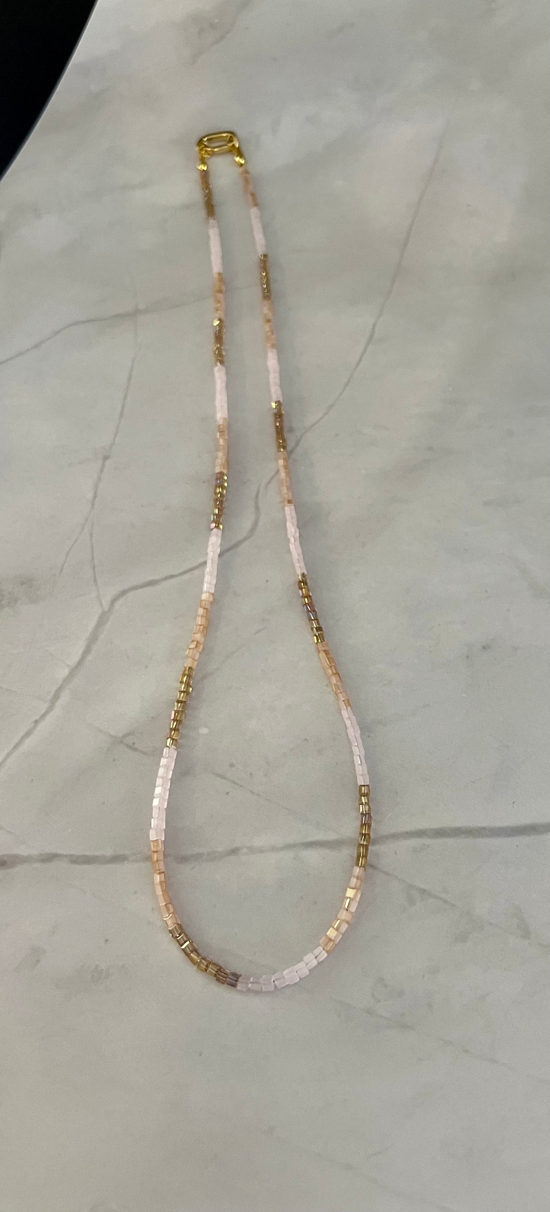 a white and gold necklace on a marble surface