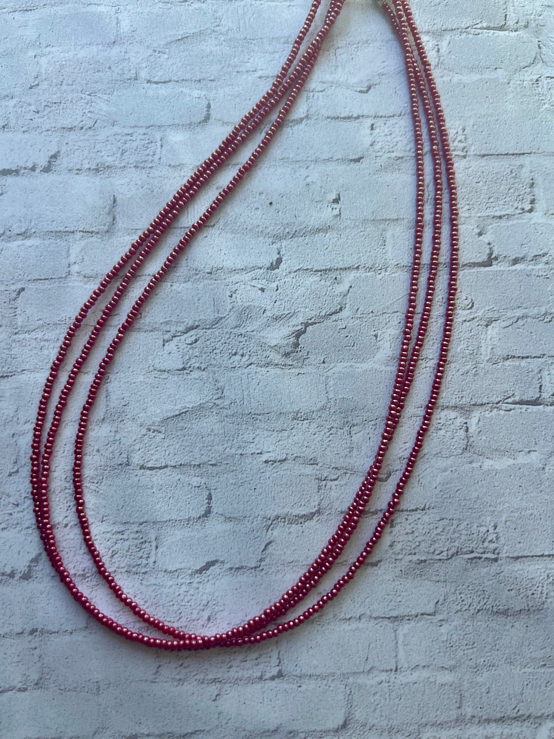 a red beaded necklace on a white brick wall