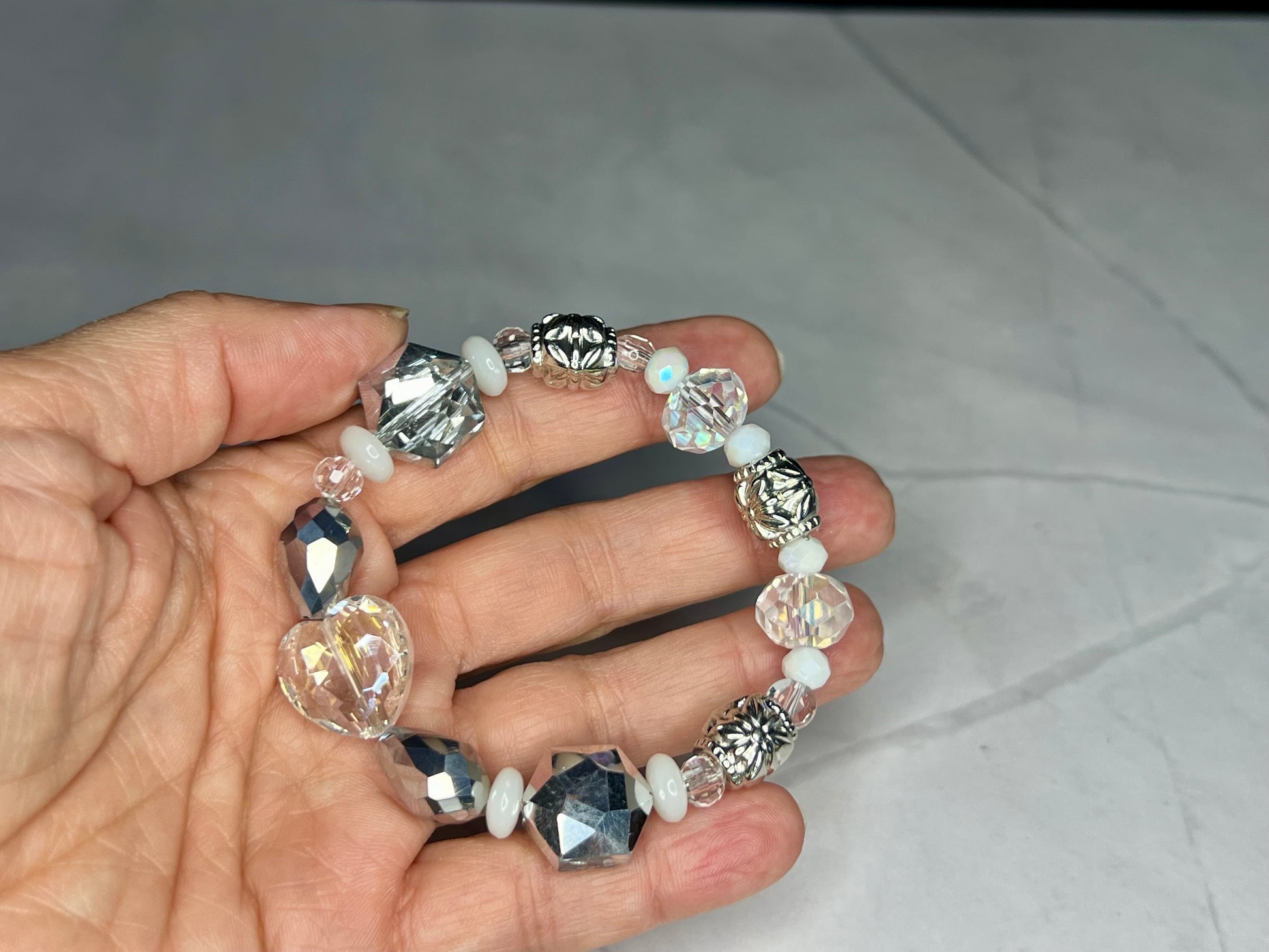 a woman's hand holding a bracelet made of glass beads