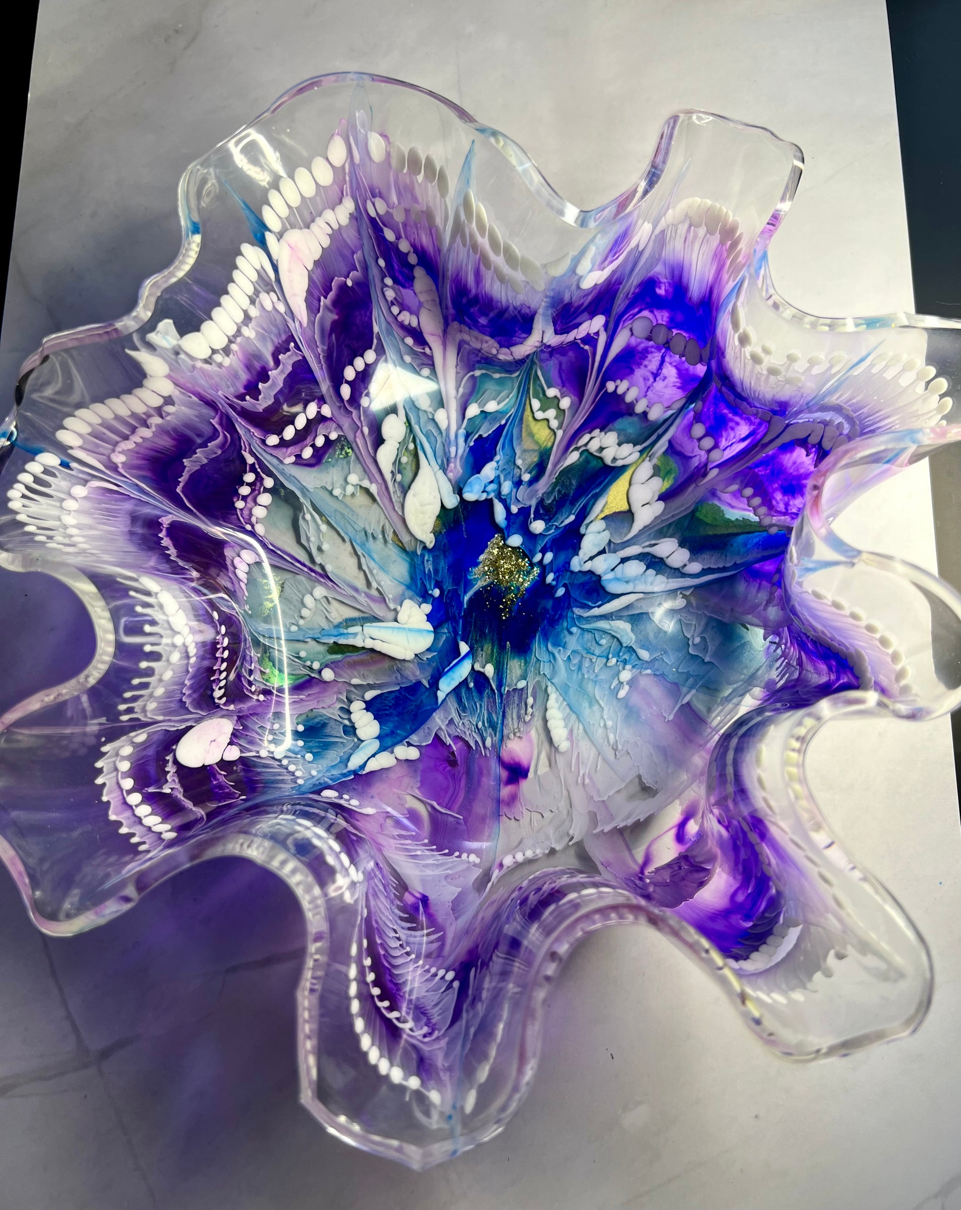 a blue and purple glass flower sitting on top of a table