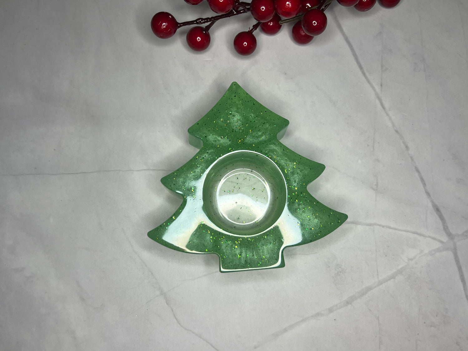 a green christmas tree shaped dish next to a branch of red berries