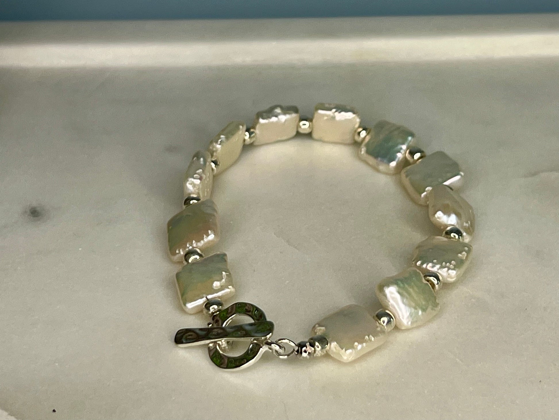 a white bracelet with a metal clasp on a table