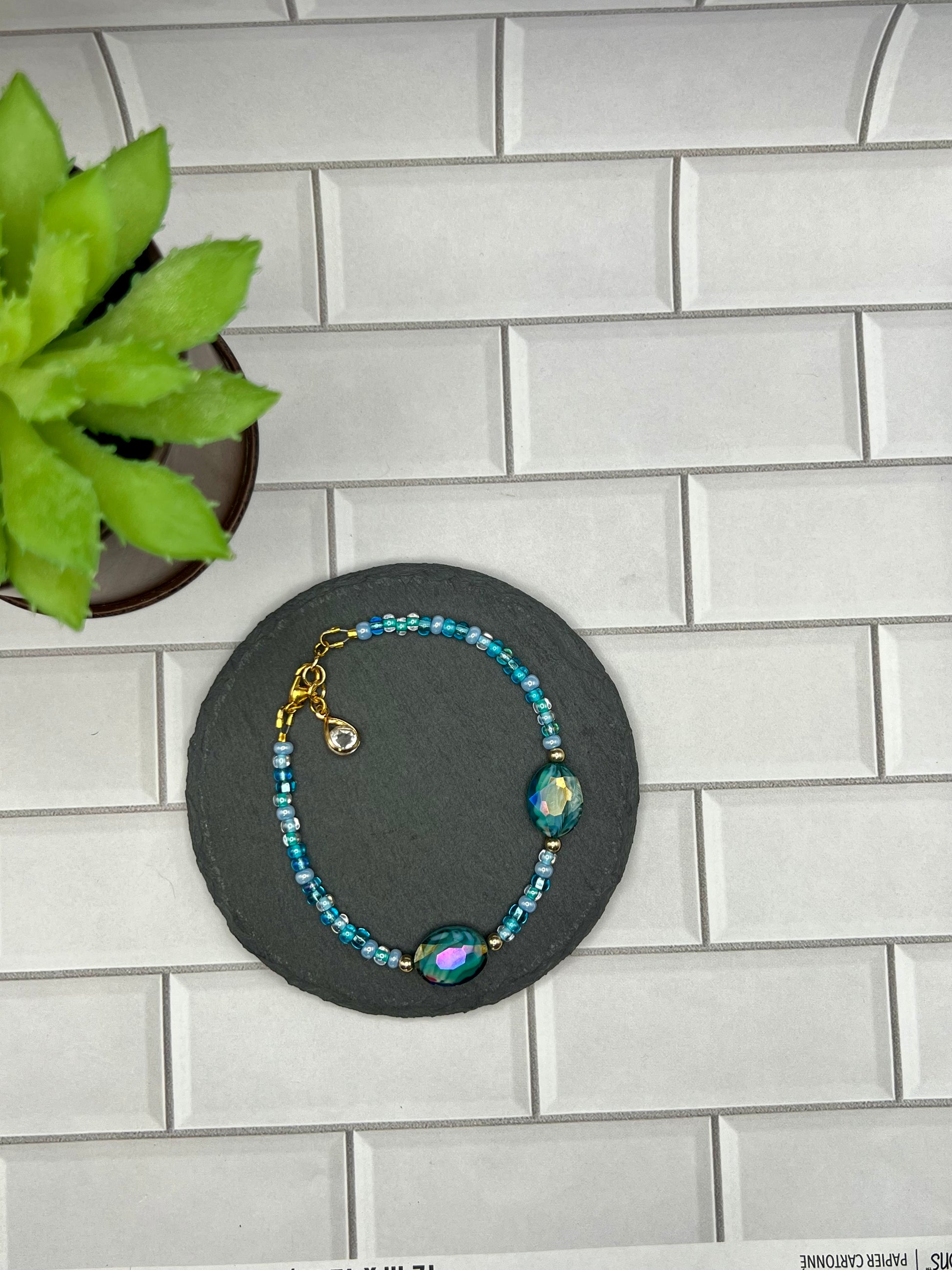 a blue beaded bracelet sitting next to a potted plant