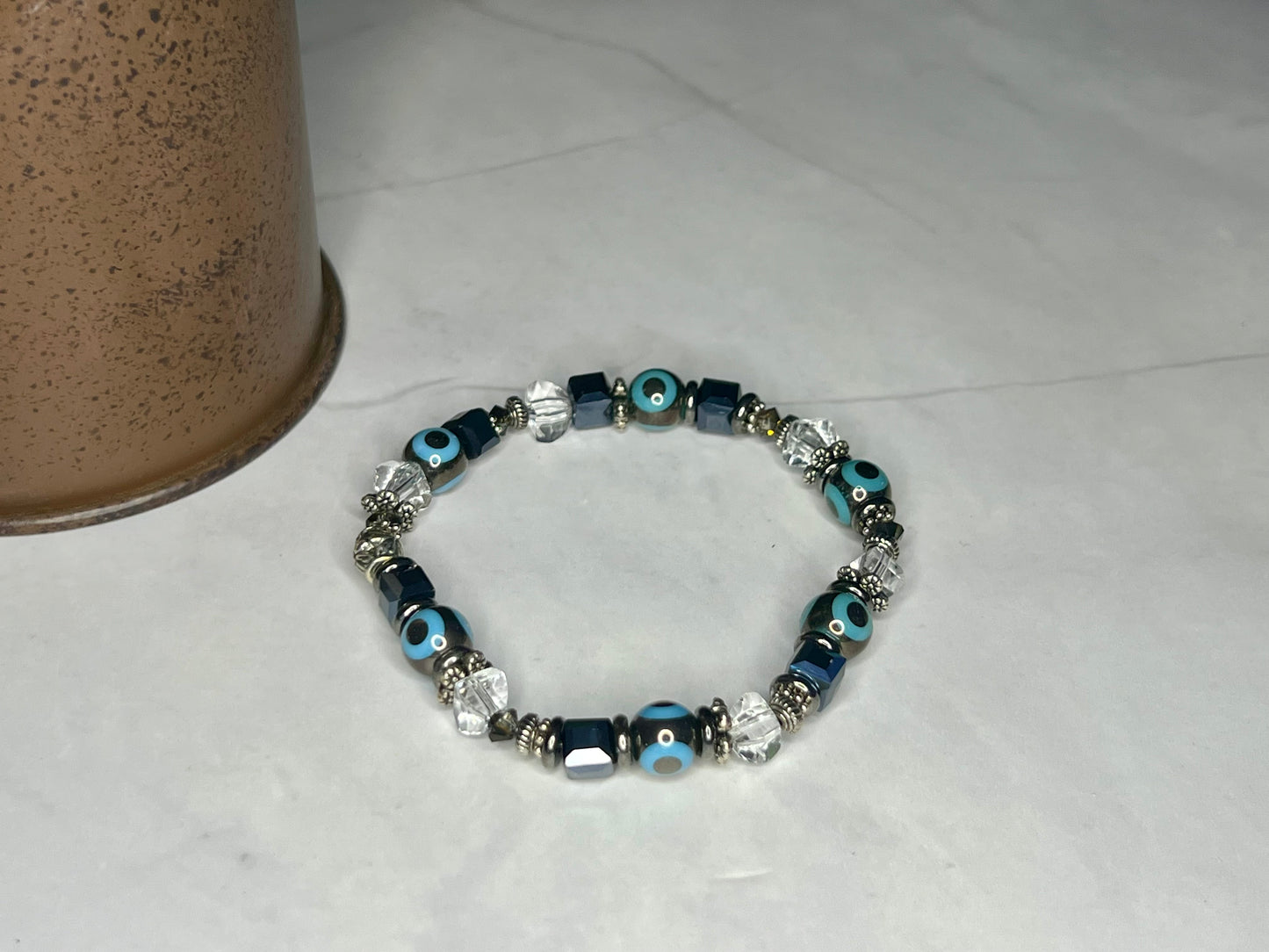 a bracelet with evil eyes on it next to a cup