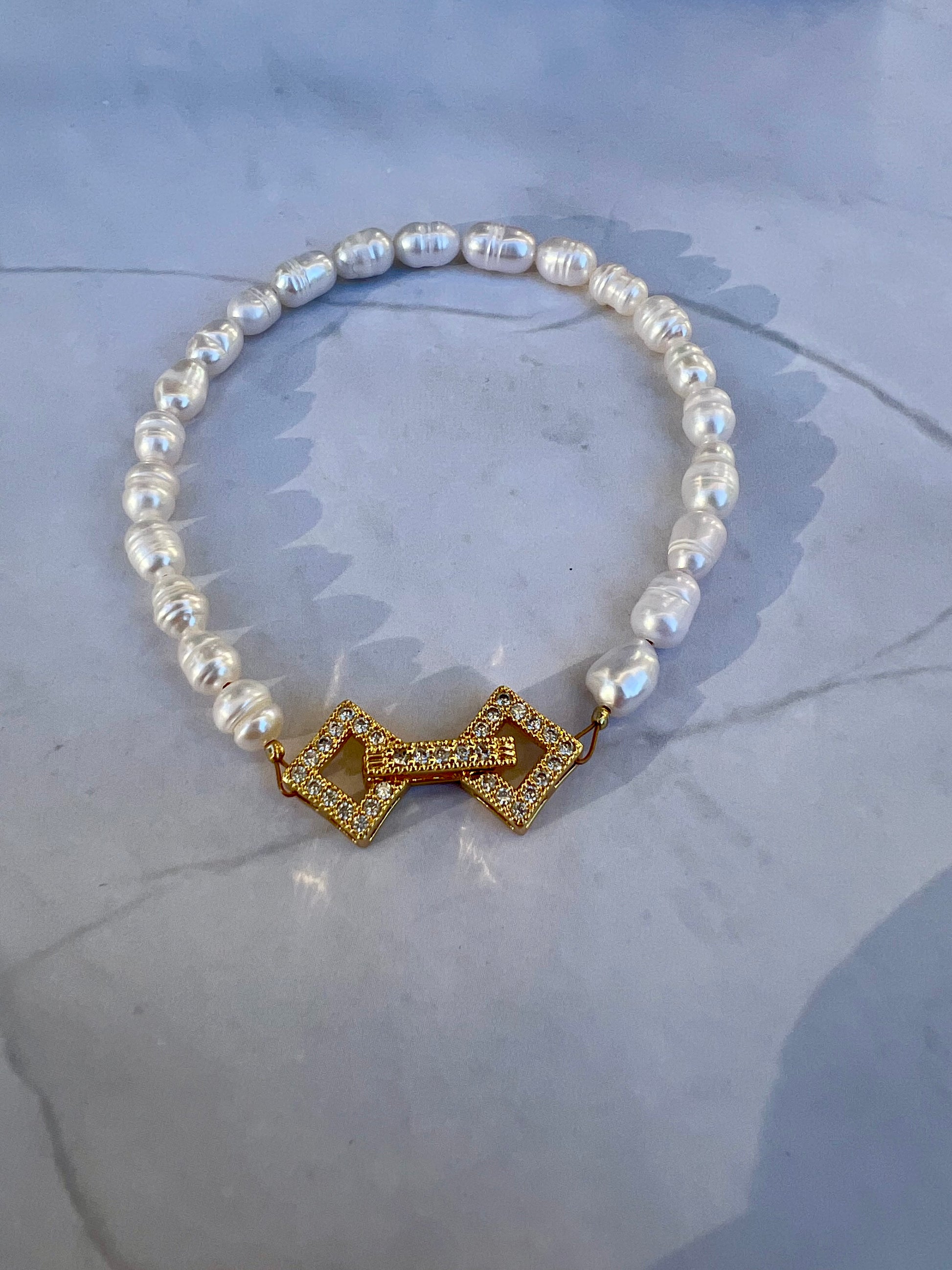 a pearl bracelet with a gold bow charm