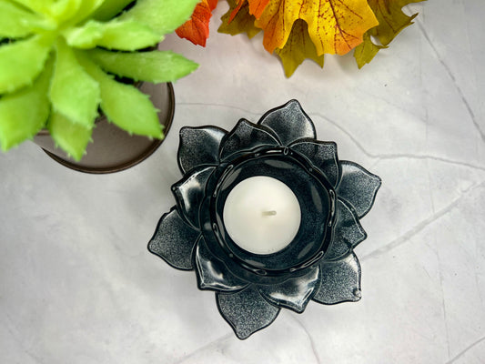 a black candle holder sitting next to a potted plant