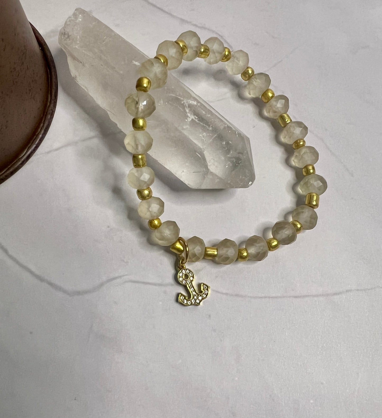 a white beaded bracelet with a gold charm