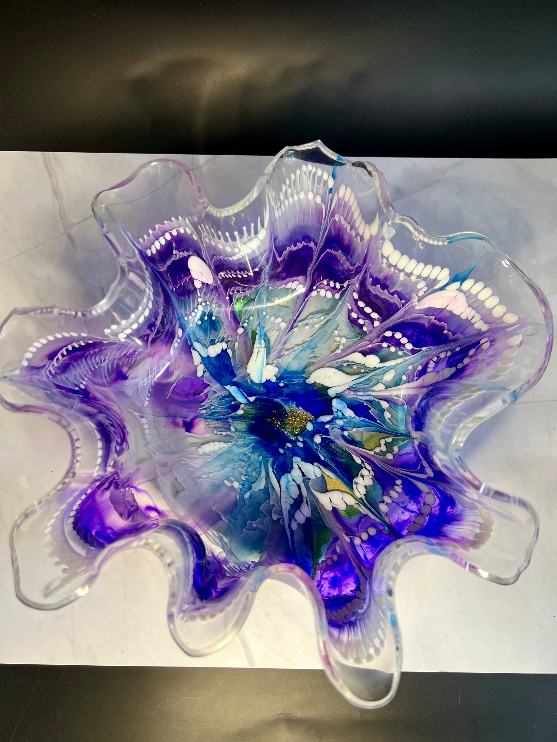 a purple and white glass flower on a table