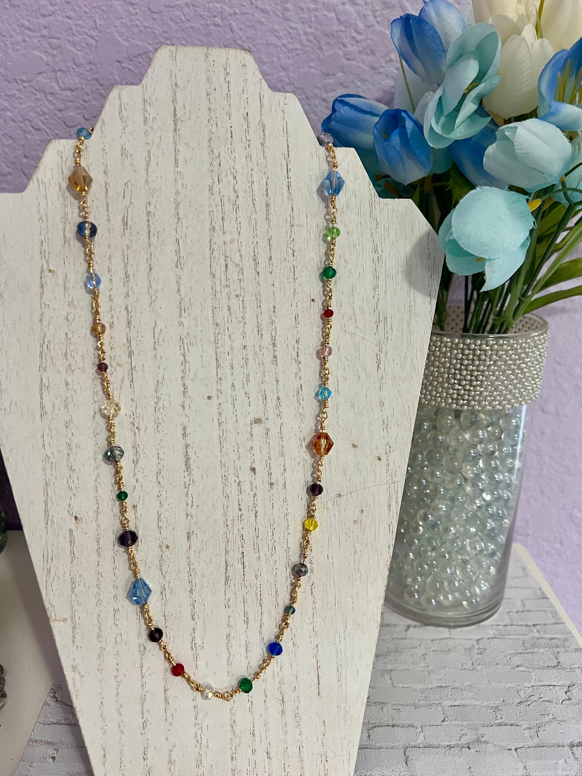 a necklace with multicolored beads on a stand