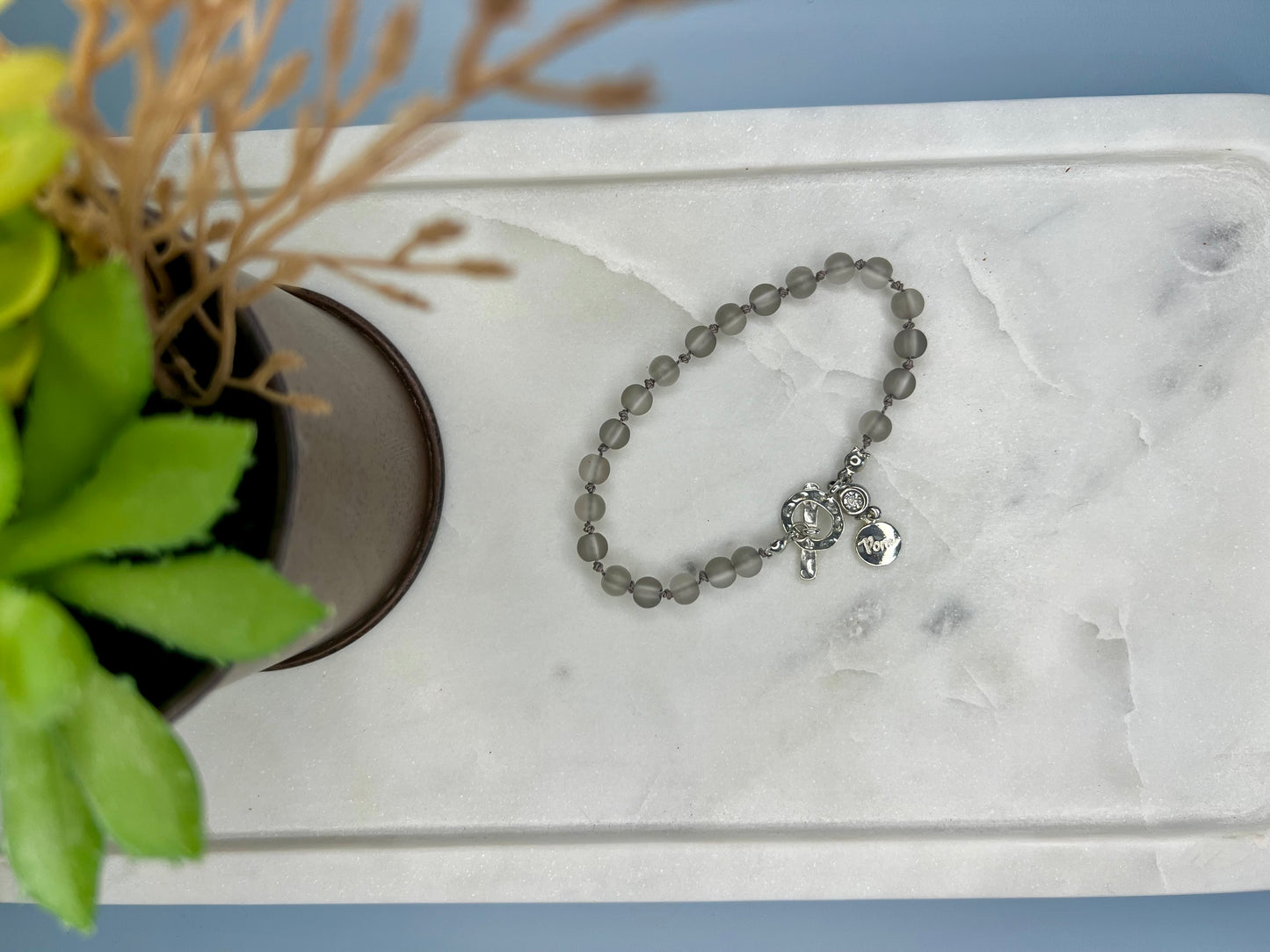 a white marble tray with a silver beaded bracelet on it