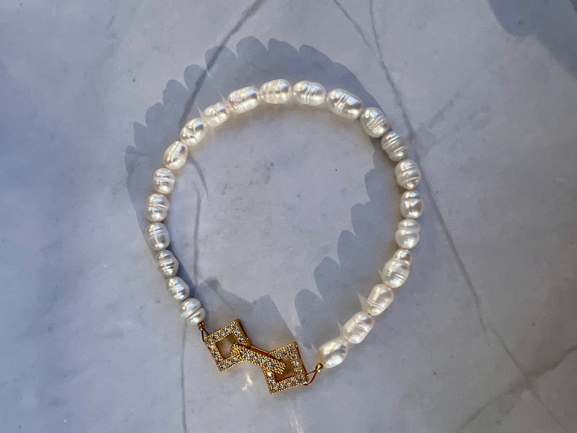 a pearl bracelet with a gold bow clasp