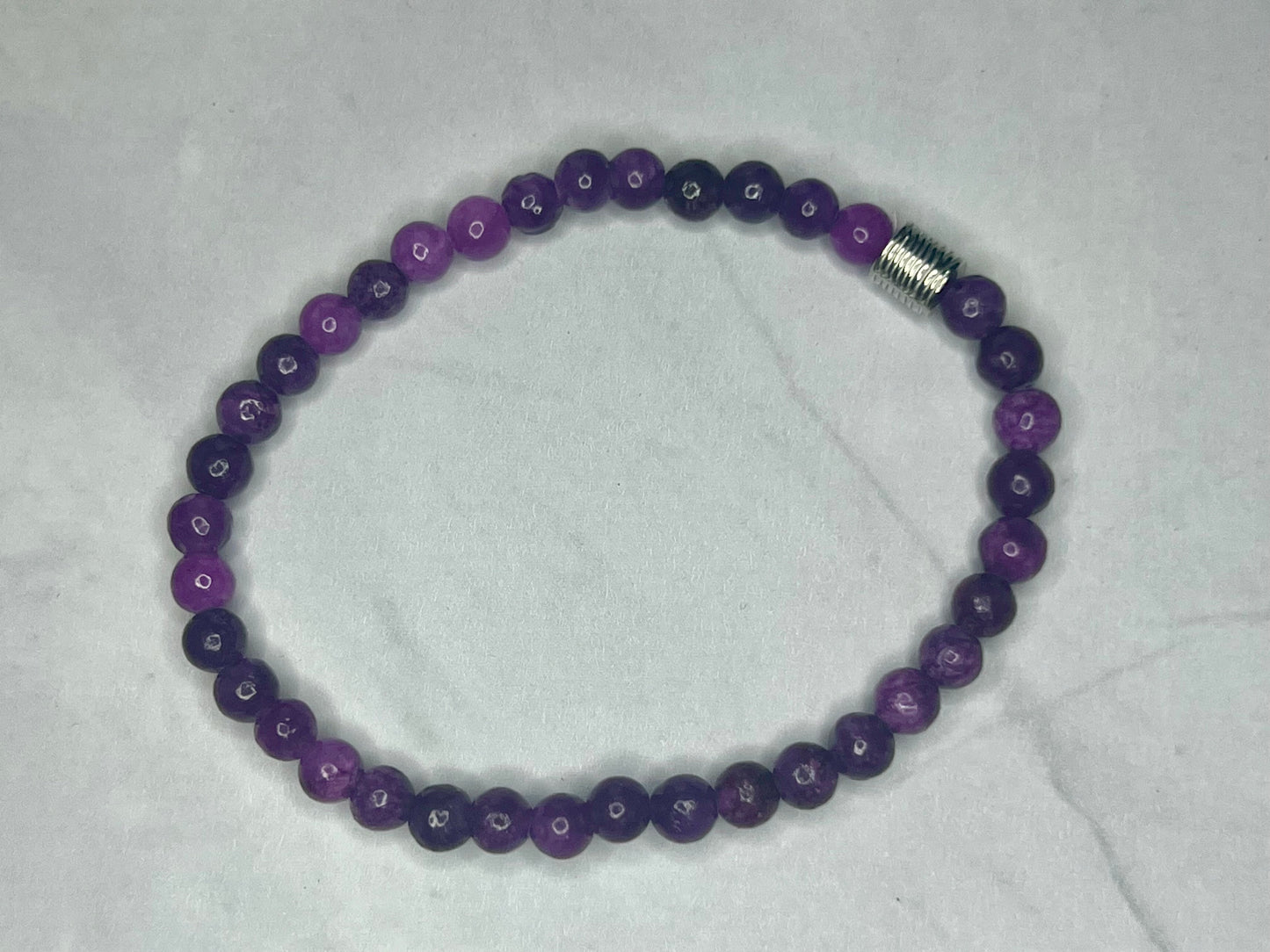 a purple beaded bracelet on a white background