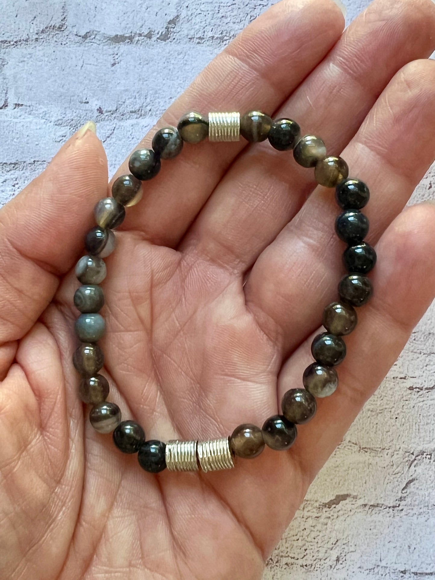 a hand holding a bracelet with a beaded clasp