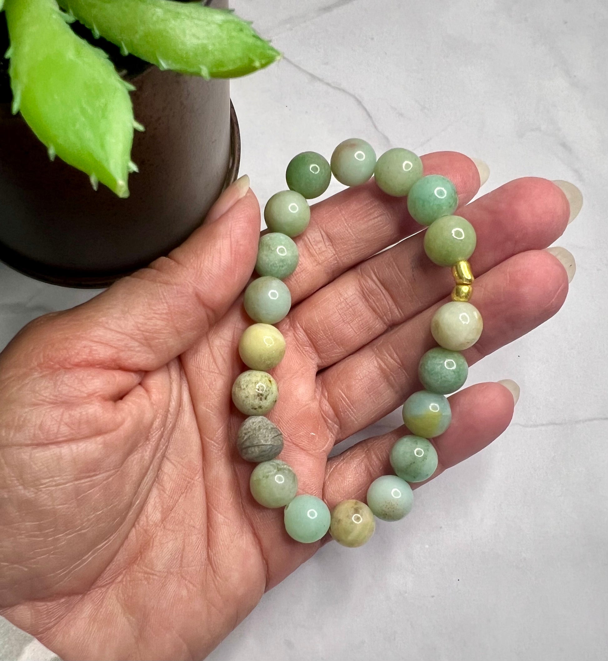 a person holding a green beaded bracelet