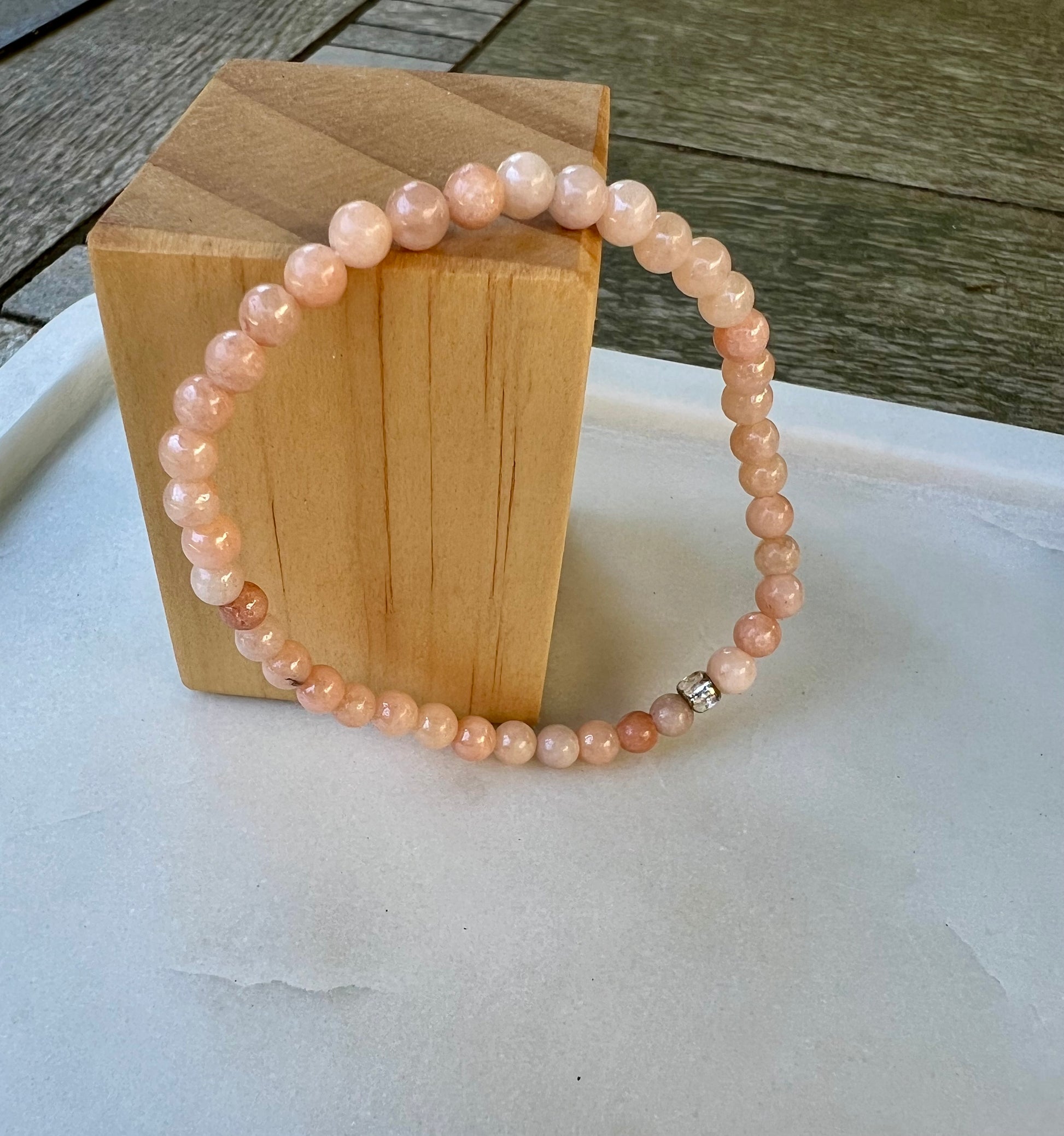 a pink beaded bracelet sitting on top of a wooden block