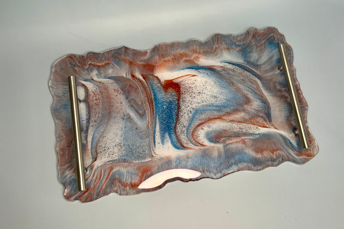 a marbled tray with metal handles on a white surface