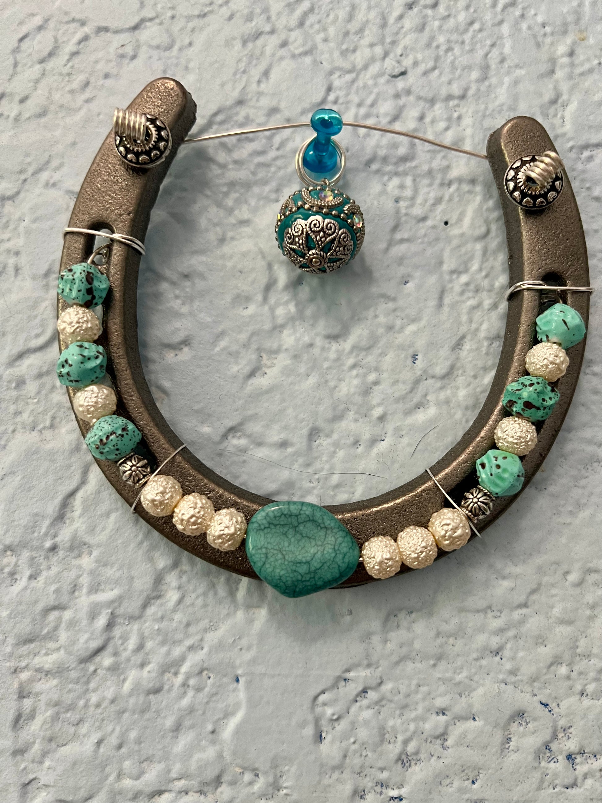 a horseshoe hanging on a wall next to a beaded necklace