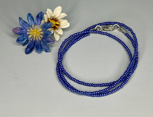 a blue beaded bracelet next to a flower