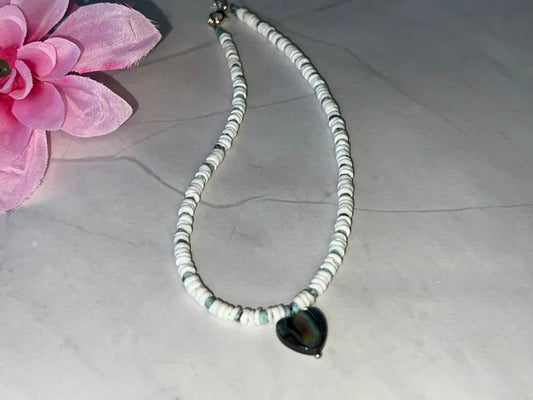 a white necklace with a black heart on it