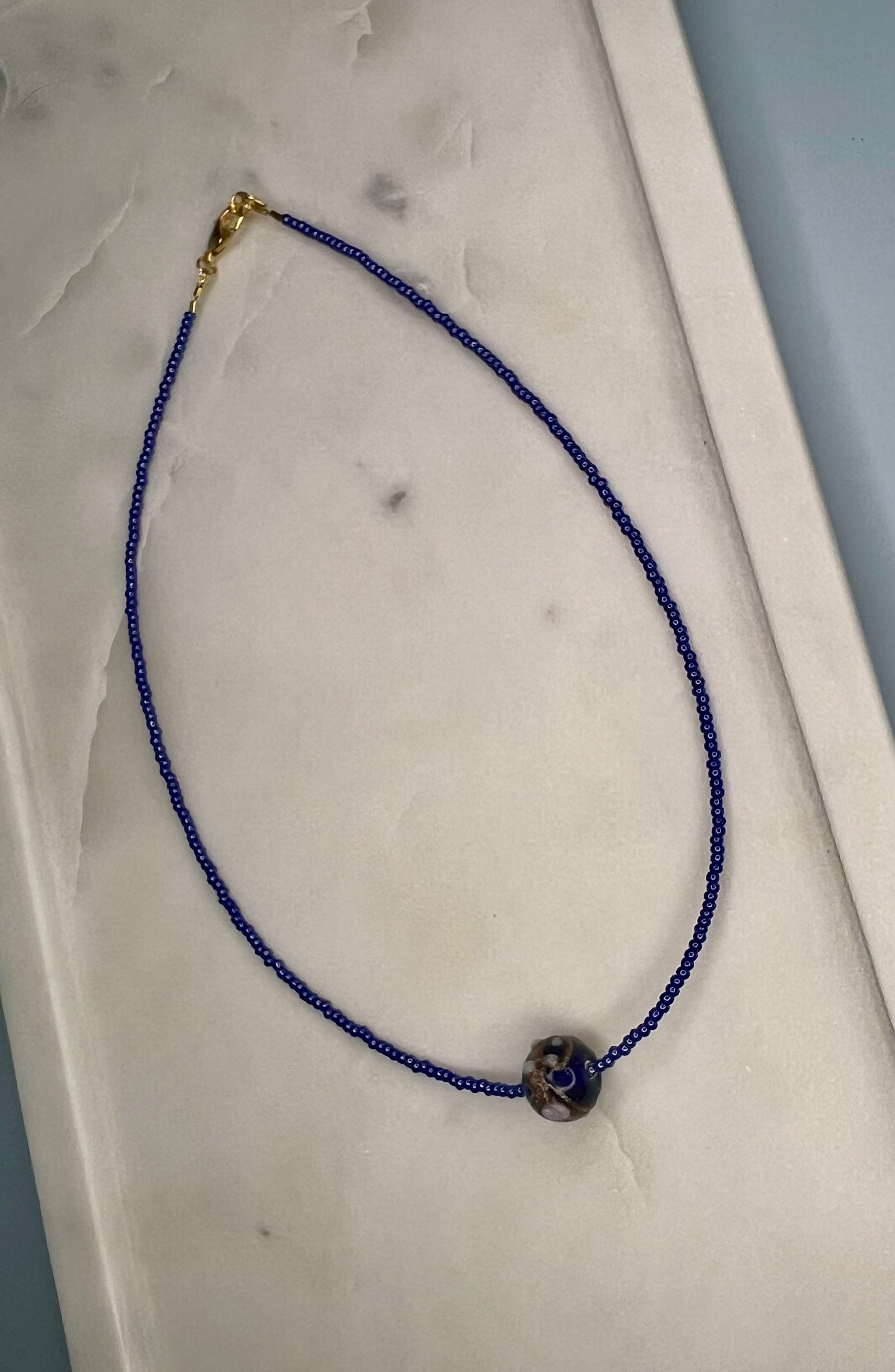 a blue beaded necklace on a white surface