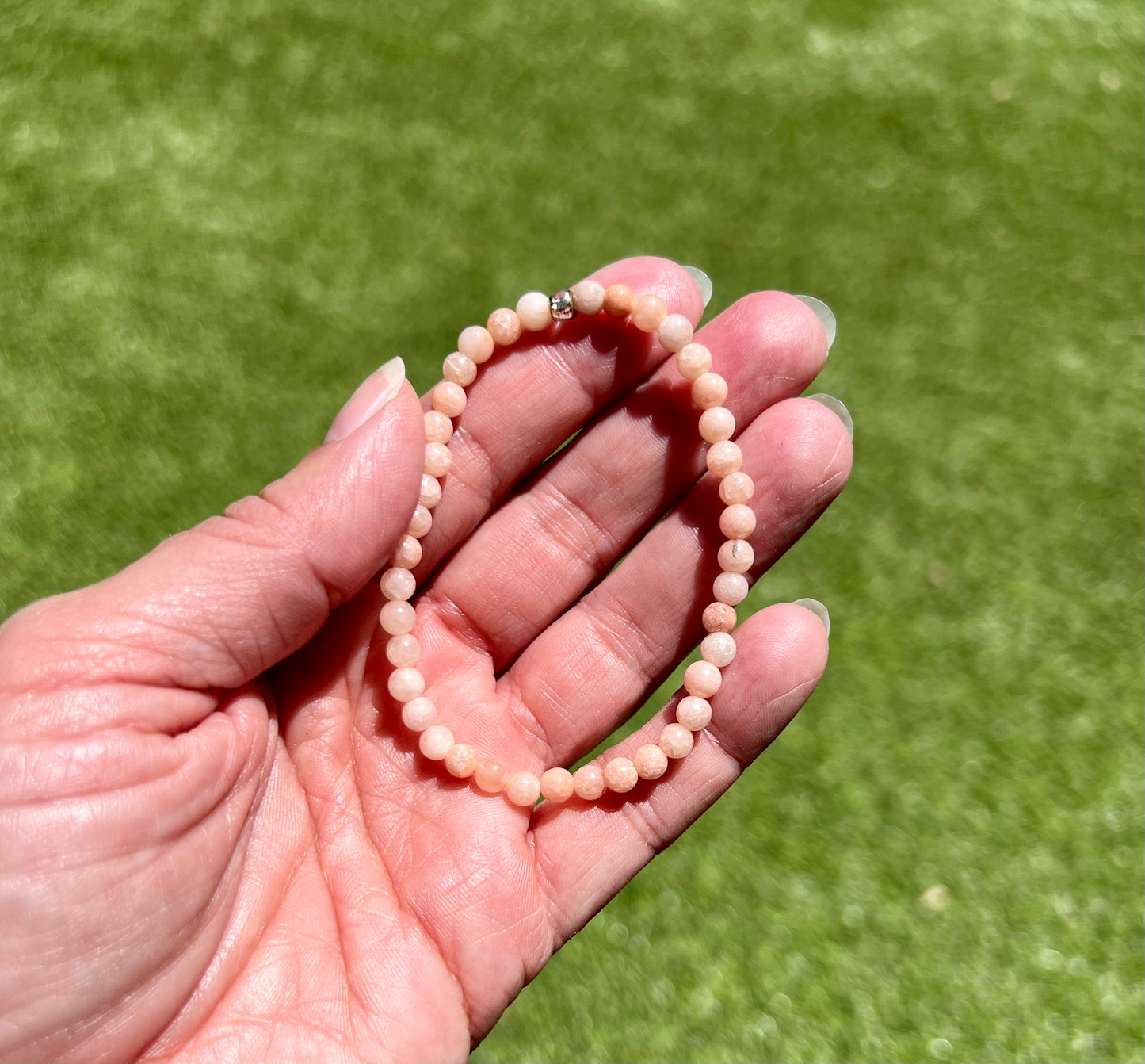 a person holding a beaded bracelet in their hand