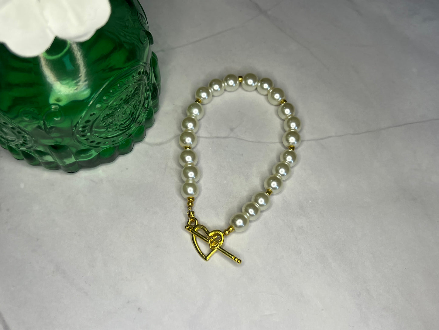 a pearl bracelet with a gold heart charm