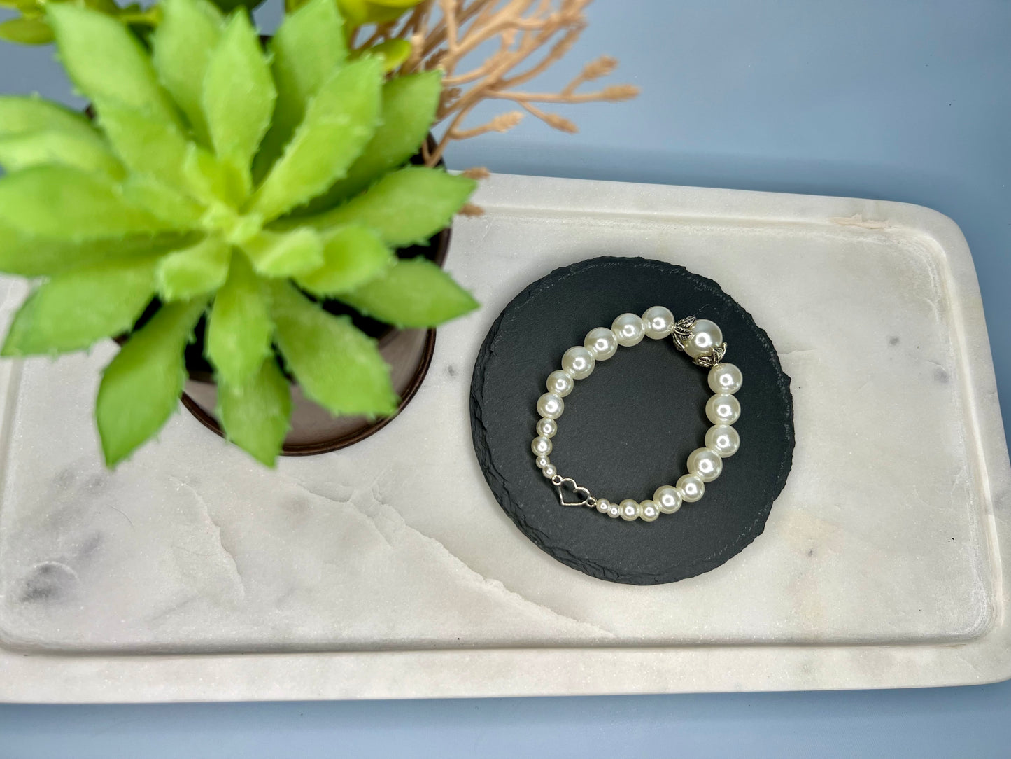 a white pearl bracelet sitting next to a potted plant