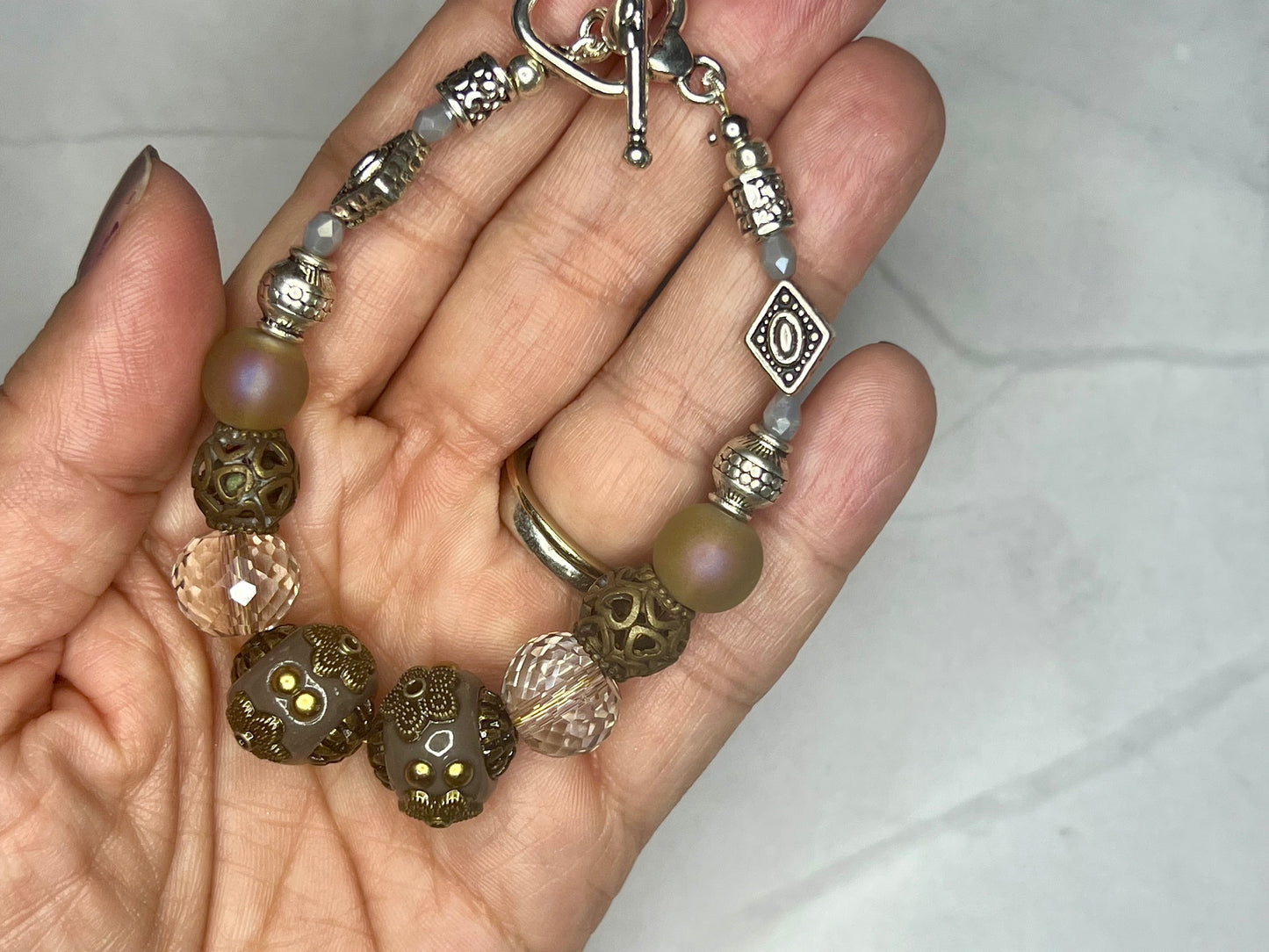 a hand holding a bracelet with beads and charms