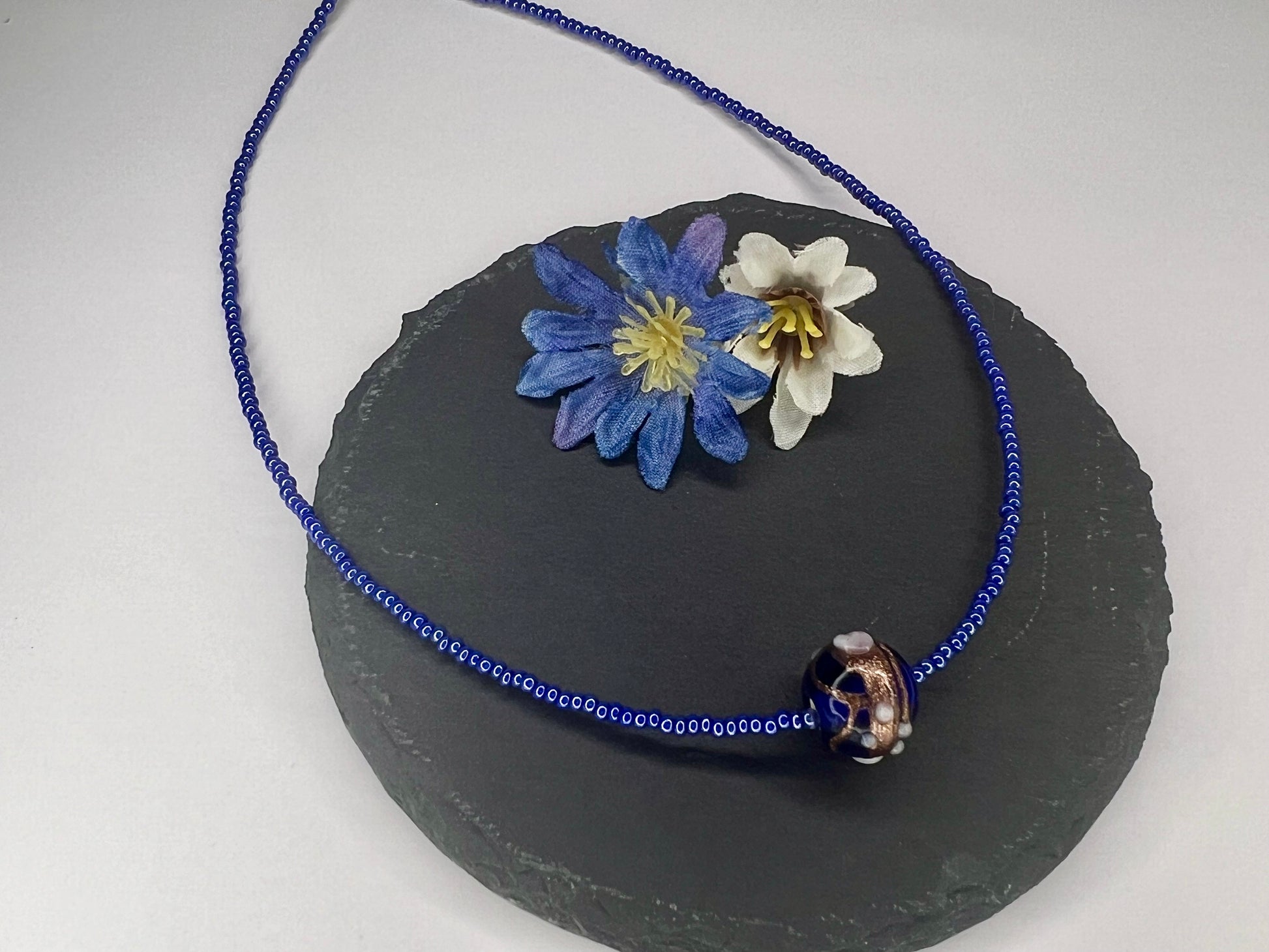 a blue beaded necklace with flowers on it