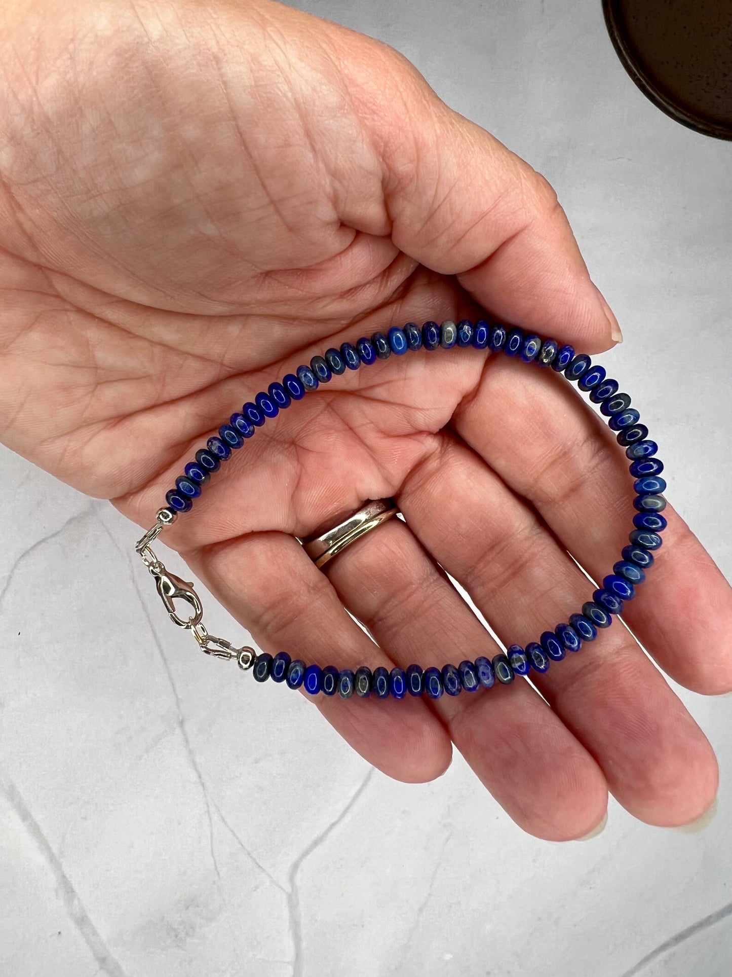 a hand holding a blue beaded bracelet