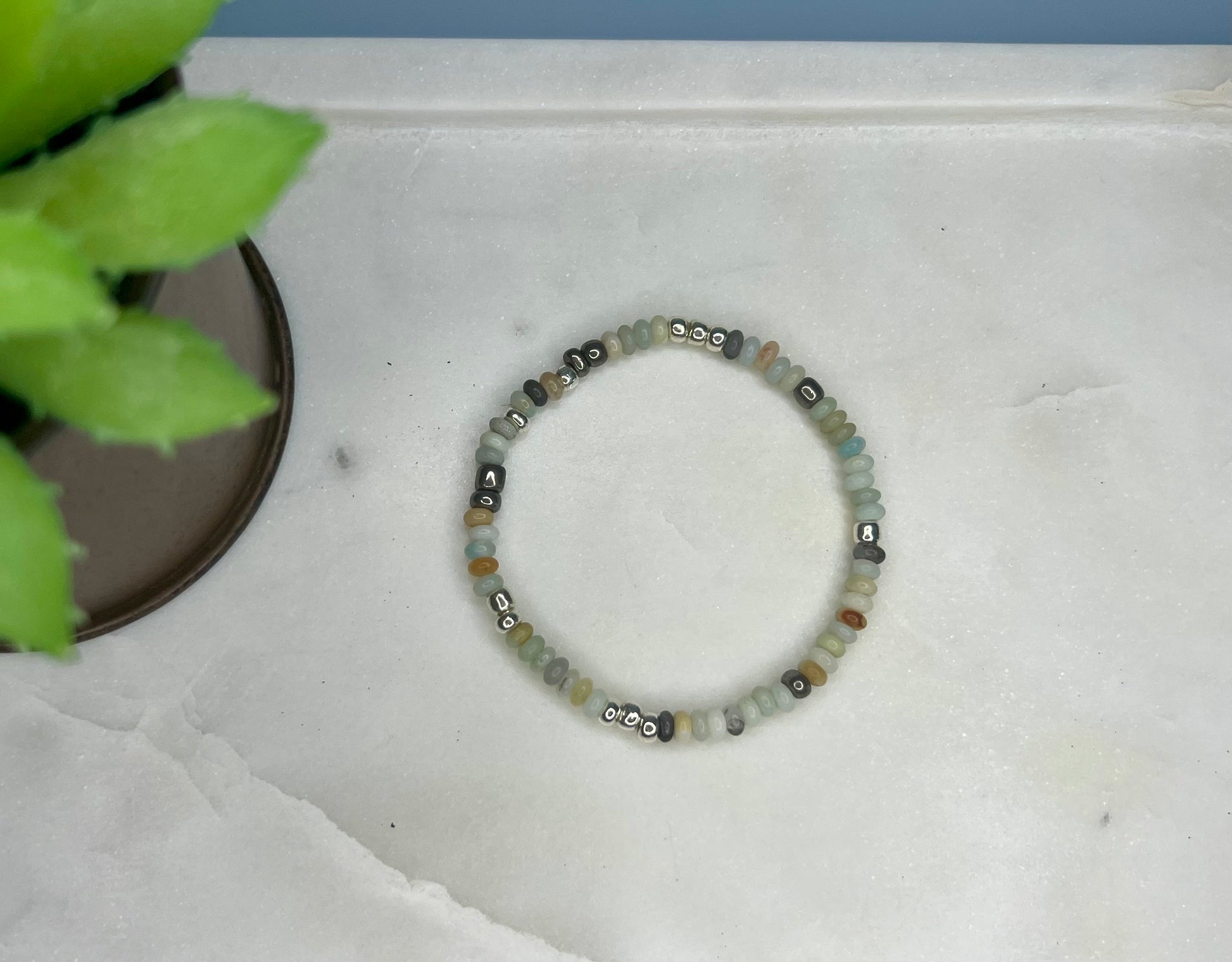 a beaded bracelet sitting on top of a table next to a potted plant