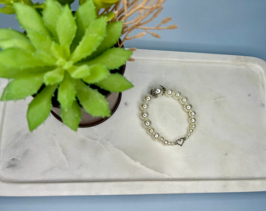 a white marble tray with a bracelet and a potted plant