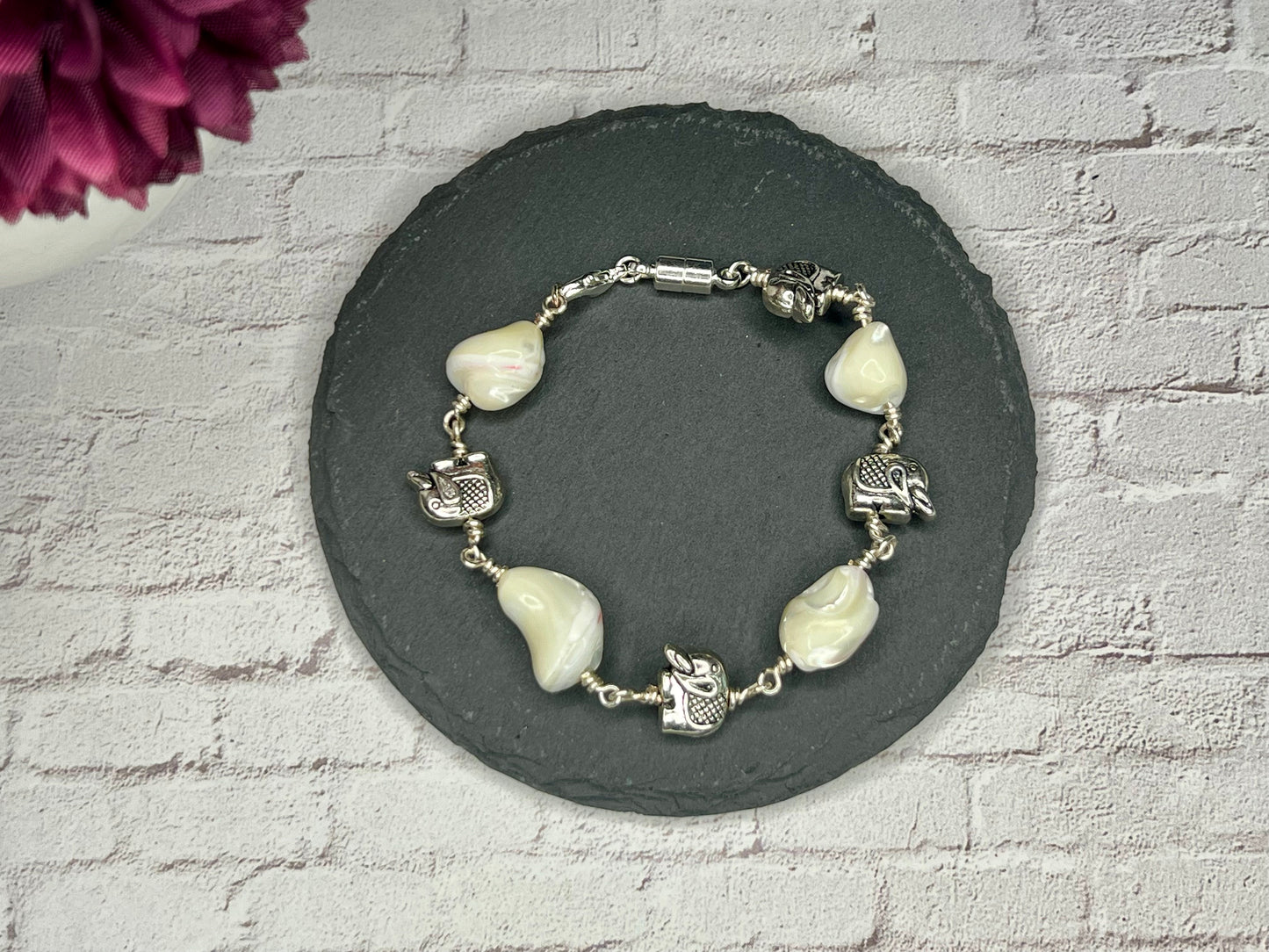 a bracelet with white beads and a silver clasp