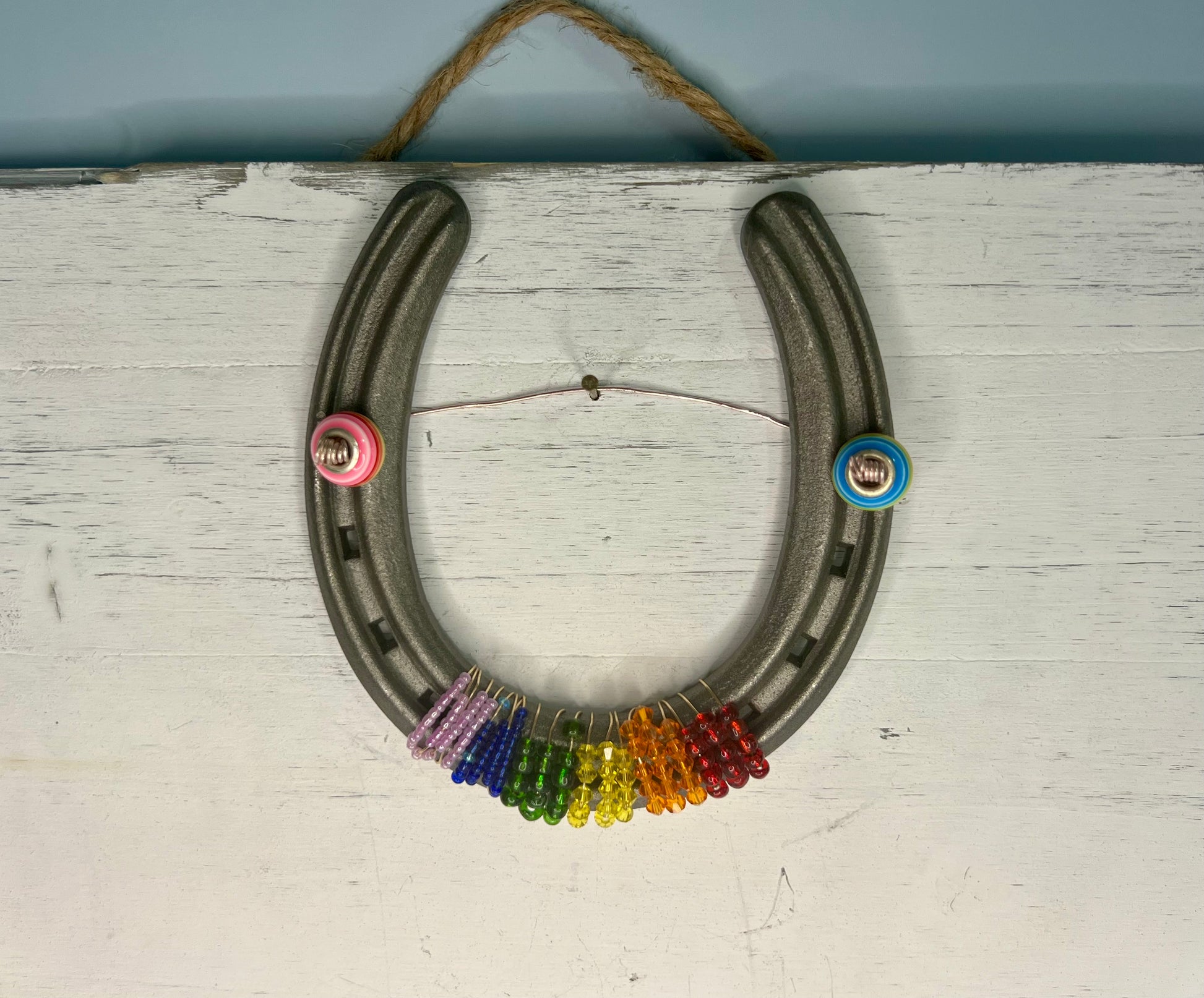 a rainbow colored necklace hanging on a white wall