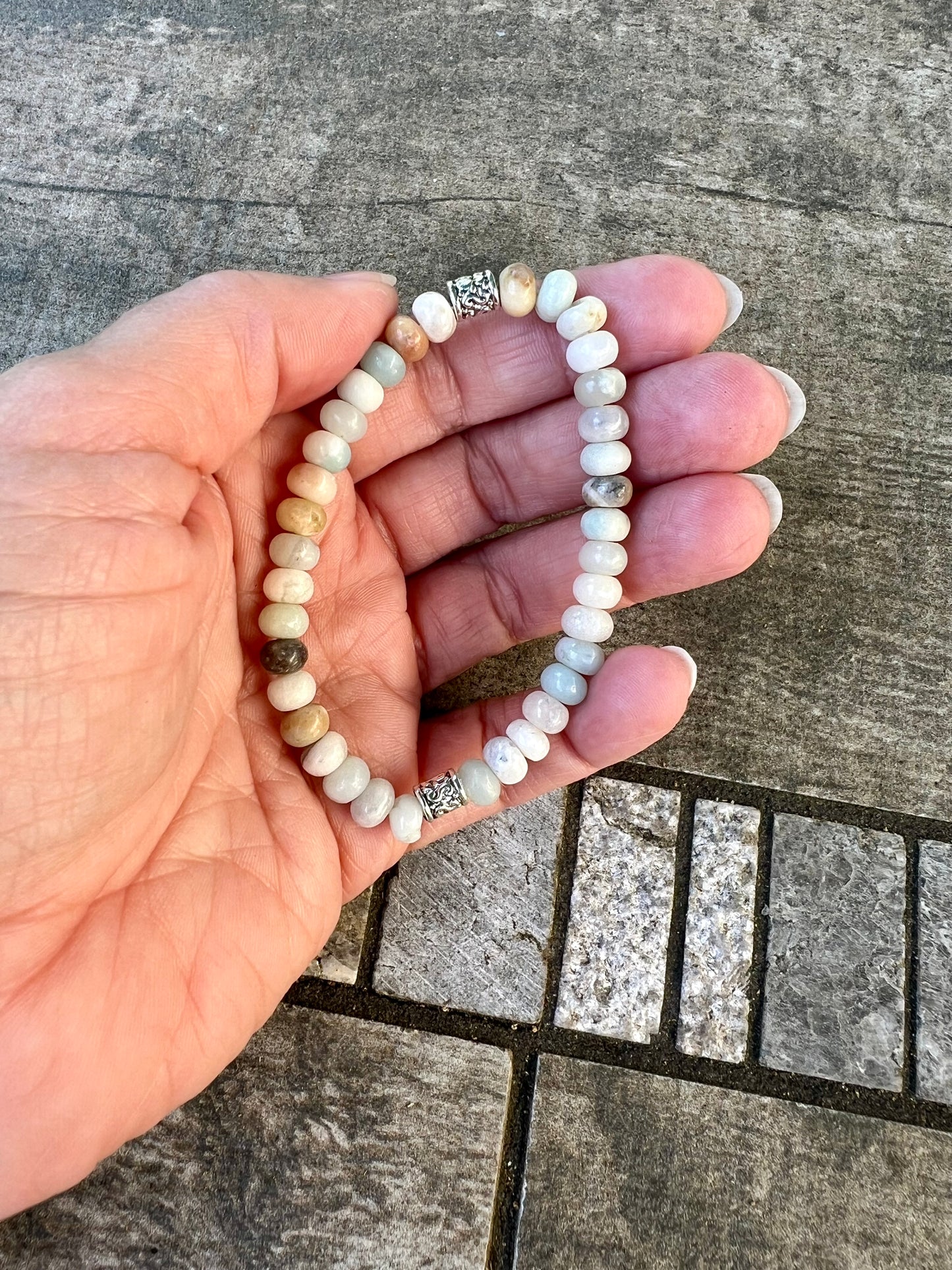 a hand holding a white beaded bracelet