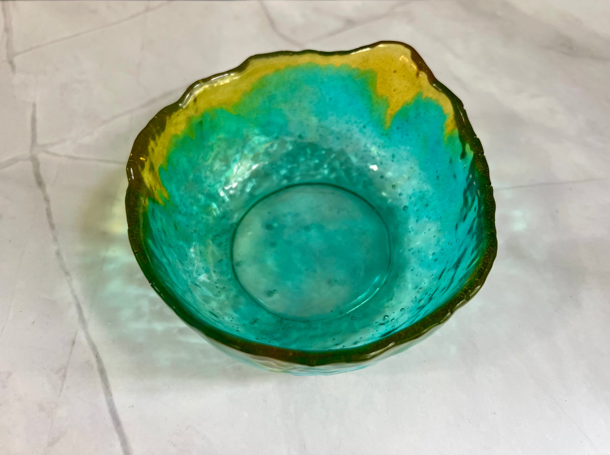 a green and yellow glass bowl sitting on a table