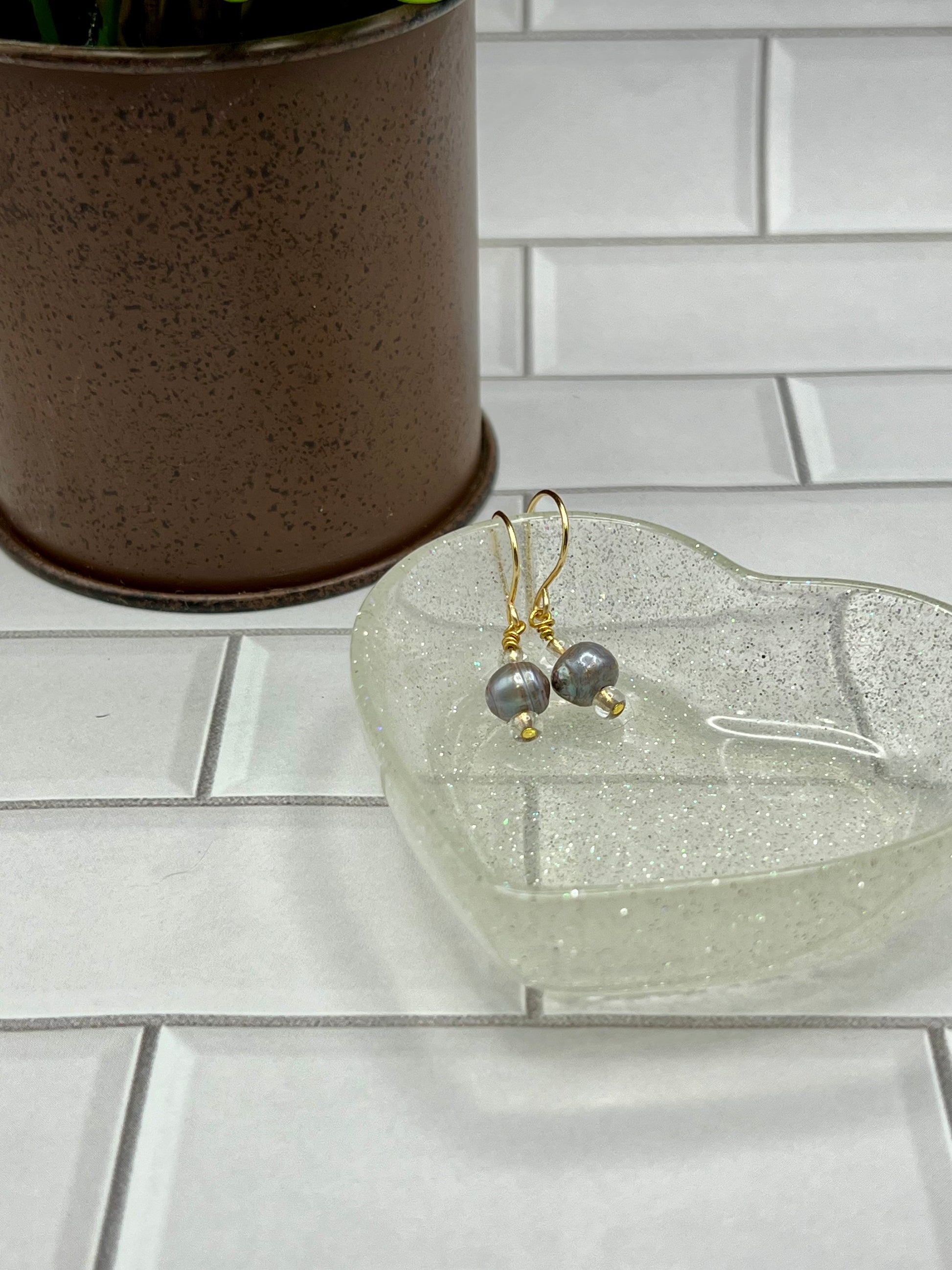 a pair of earrings sitting on top of a glass bowl