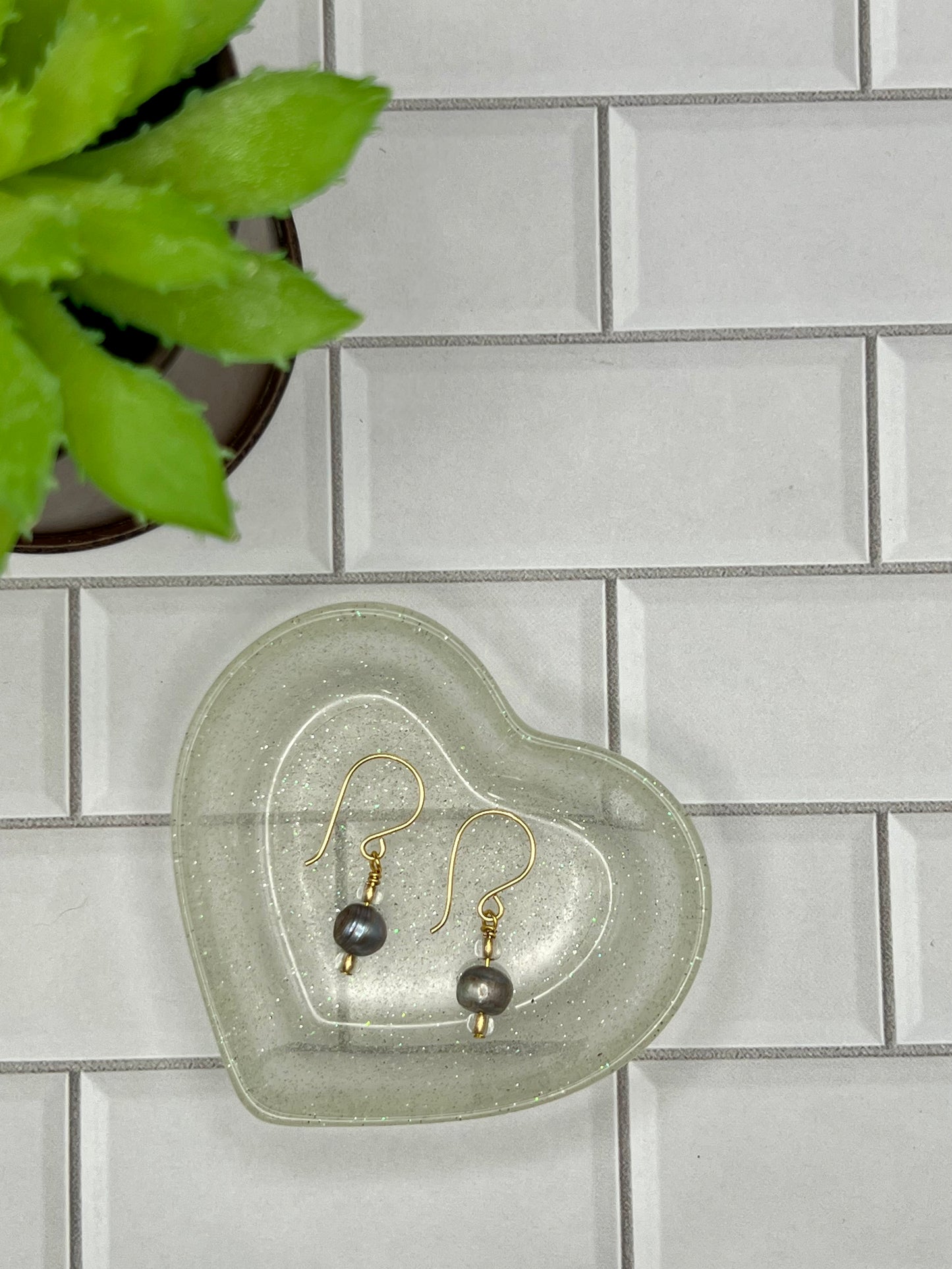 a pair of earrings sitting on top of a glass heart