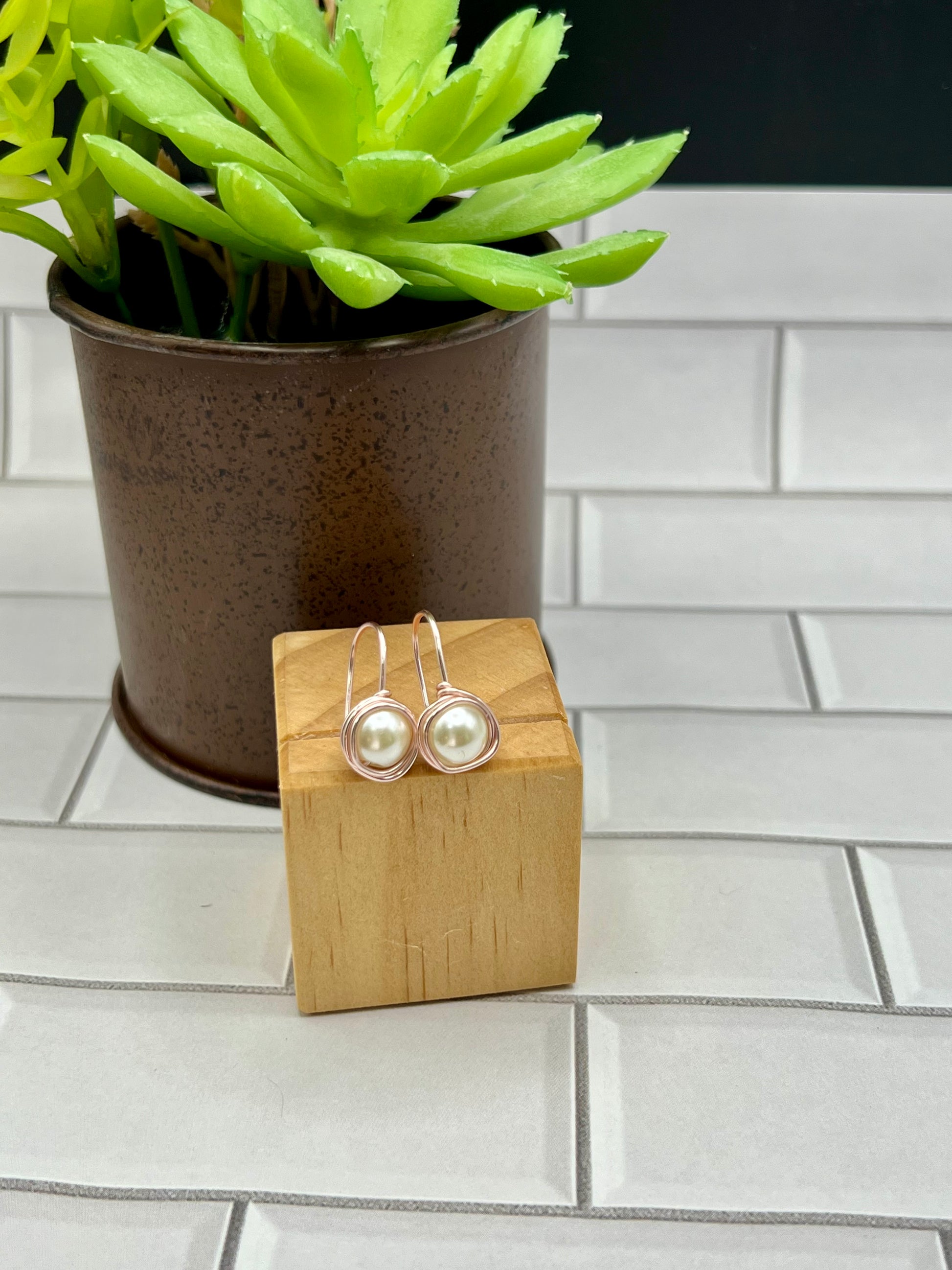 a pair of earrings sitting on top of a wooden block