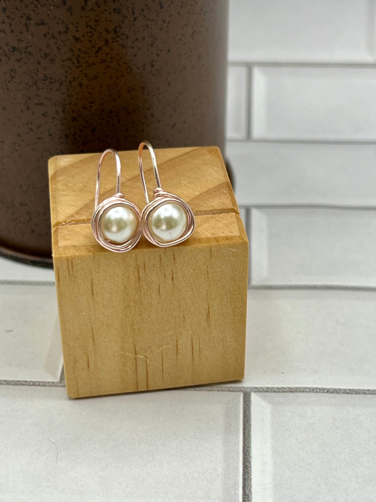 a pair of earrings sitting on top of a wooden block